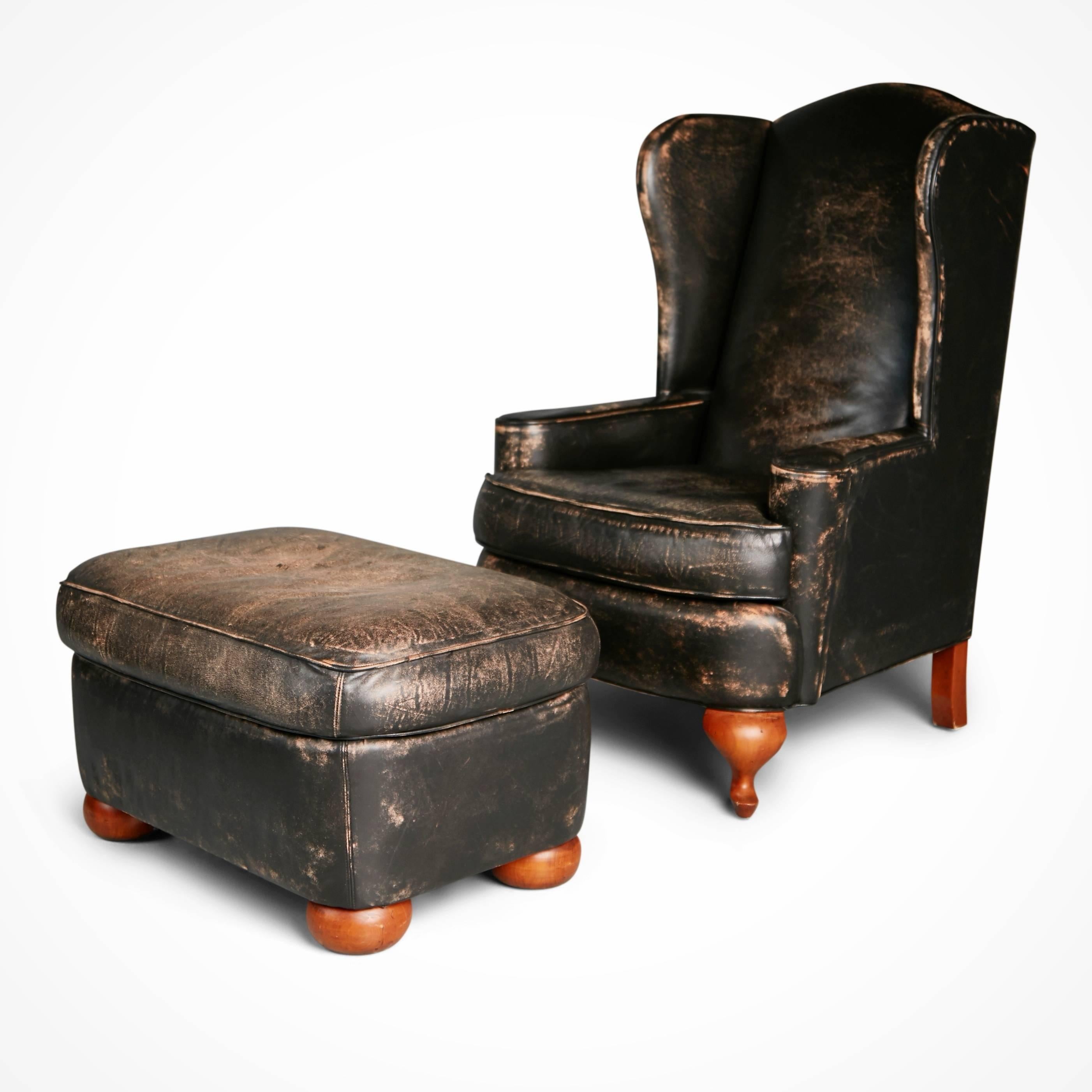 Pair of Ralph Lauren for Henredon leather wingback chairs and matching ottomans. These wing chairs with tall backs and counterpart ottomans are upholstered in black leather which features a distressed look to simulate age and use. The highly