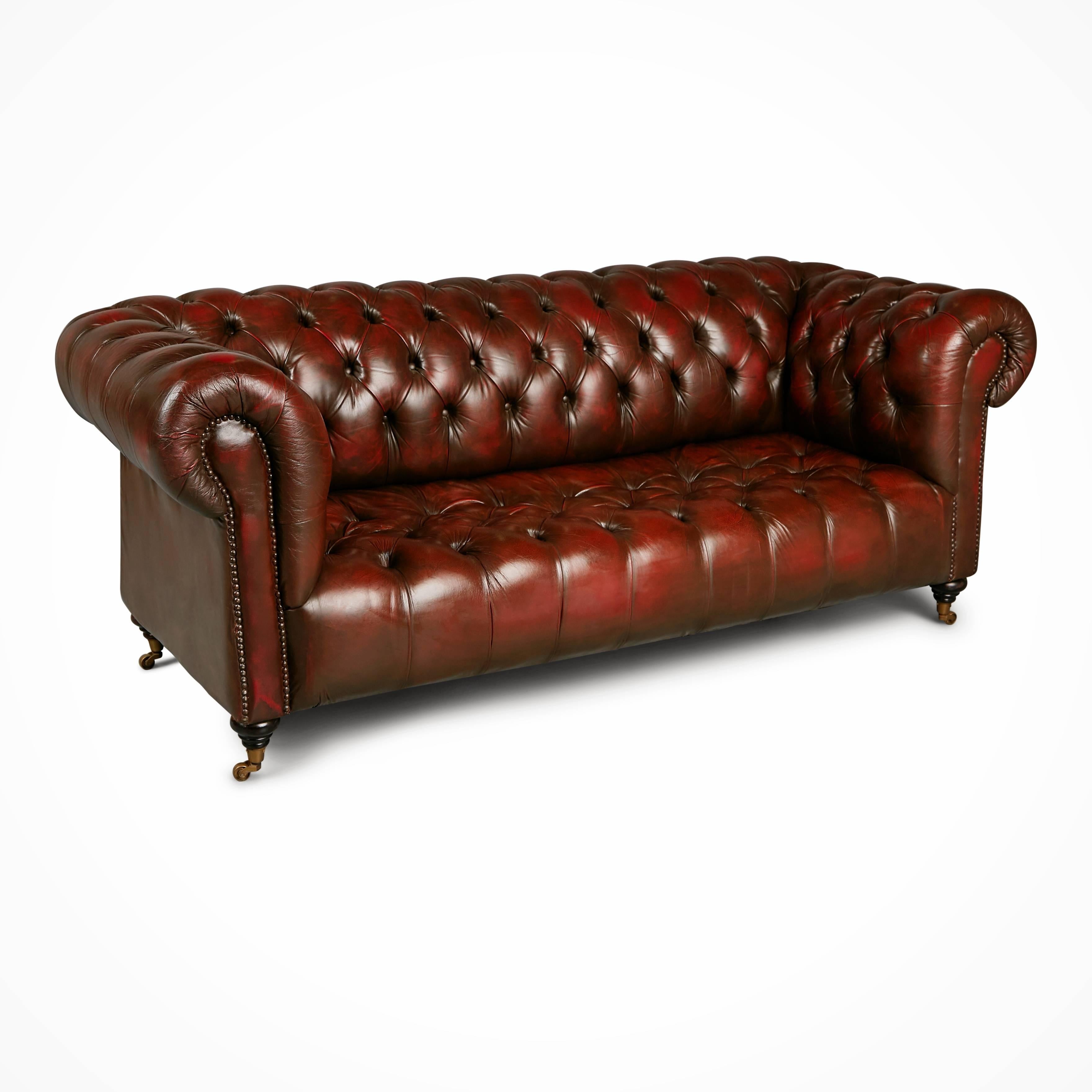 Handsome Chesterfield sofa displaying the classic attributes of this time honored design including the rolled back and armrests. This sofa is upholstered in a rich oxblood leather which has been intentionally distressed as well as having developed
