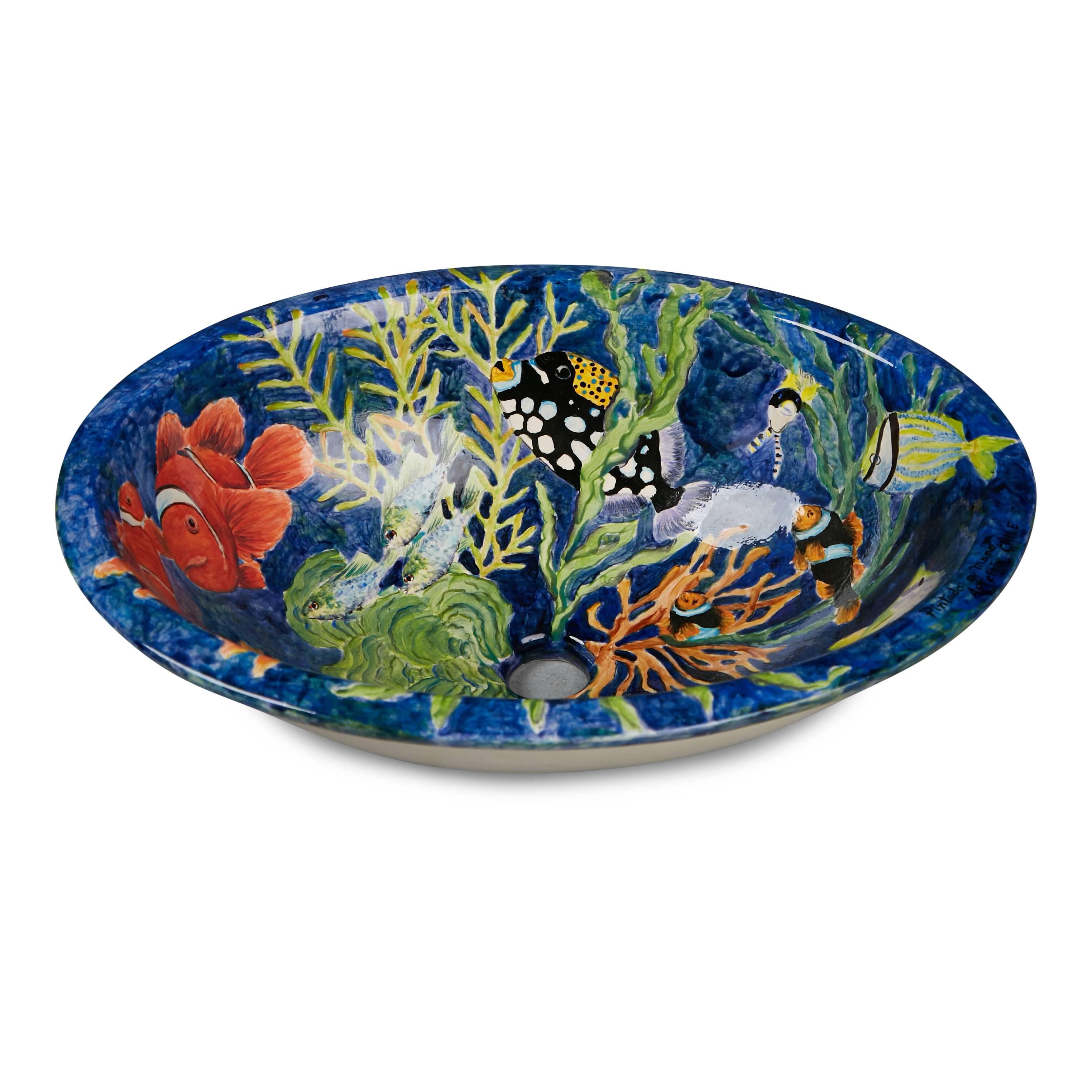 Beautifully hand painted porcelain oval sink. This aquatic scene has been executed with fine detail, portraying an array of colorful fish and plant life on a cobalt blue background. Painted on the corner is Pintado a Mano Artemix Chile. 

This