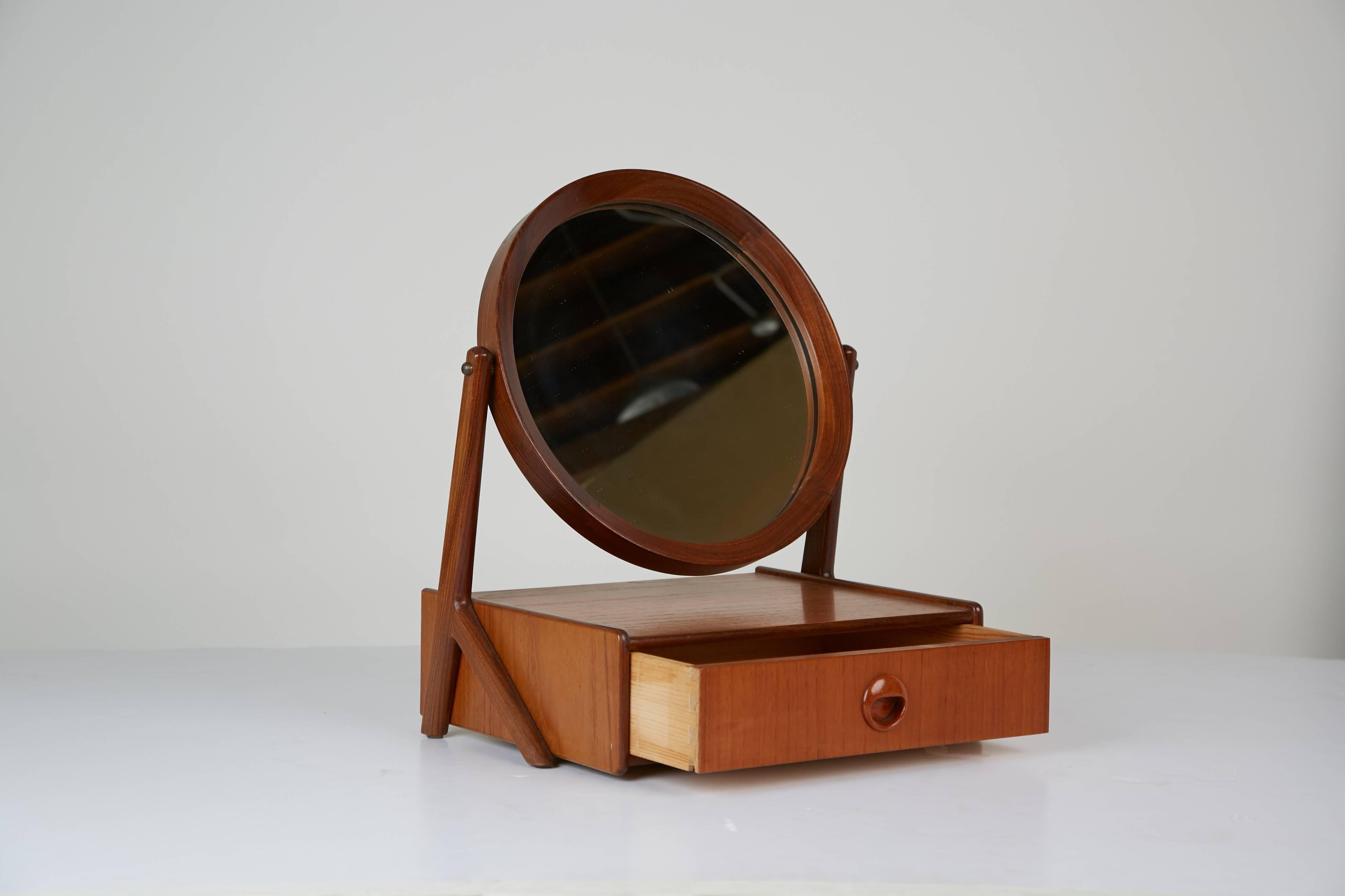 Beautifully crafted Talgos Mobelfabrikk vanity mirror, made in Todalen, Norway. This recently refinished dressing mirror is fabricated from teak with a circular mirror suspended and secured onto two extended sculptural wood pieces, allowing for the