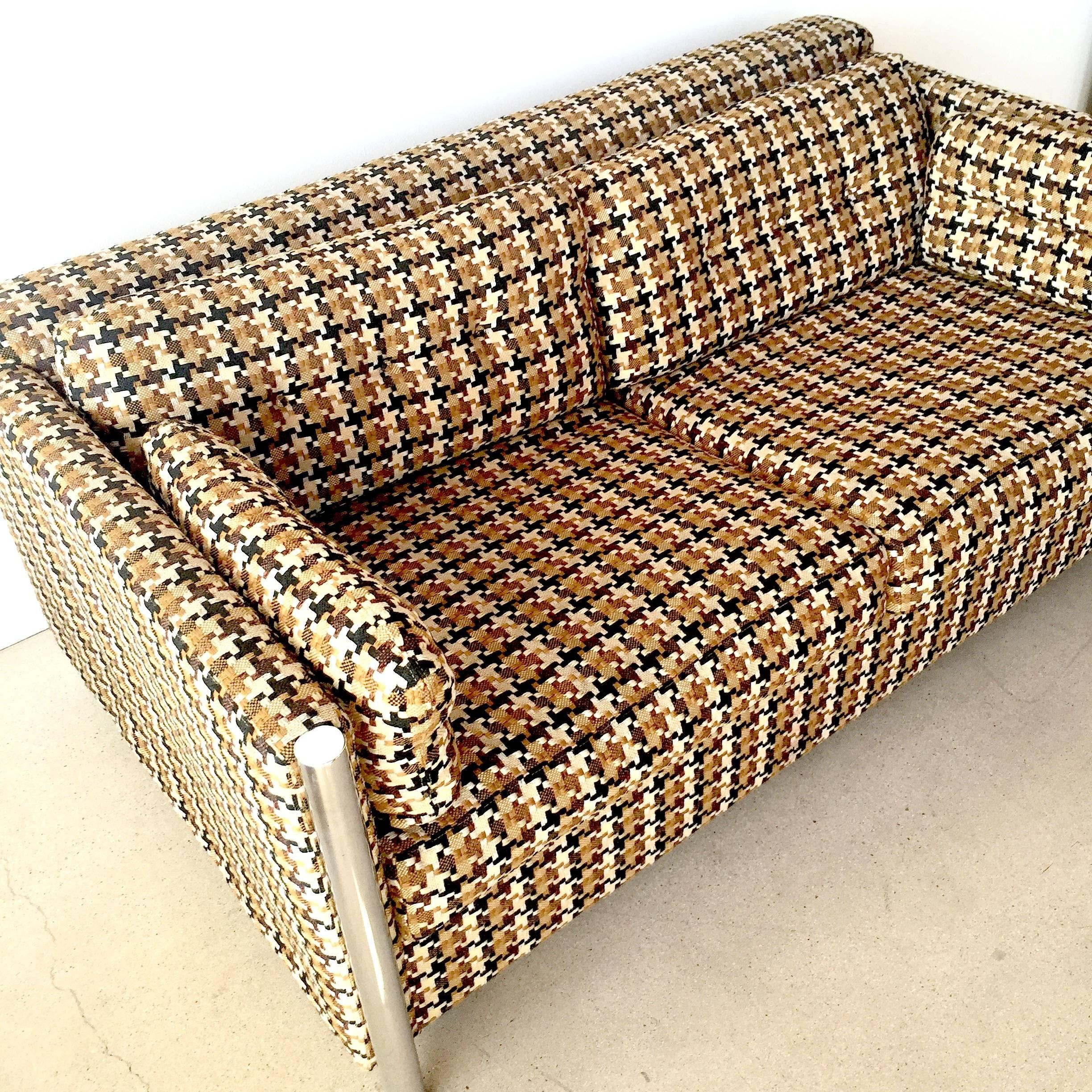 Fabulous 1970s retro sofa bed from Selig showcase. Cushions come off and bed pulls out with a full size mattress. There is also a packet of extra fabric included for arm covers or headrests. Mint condition houndstooth fabric. Chrome leg accents.
