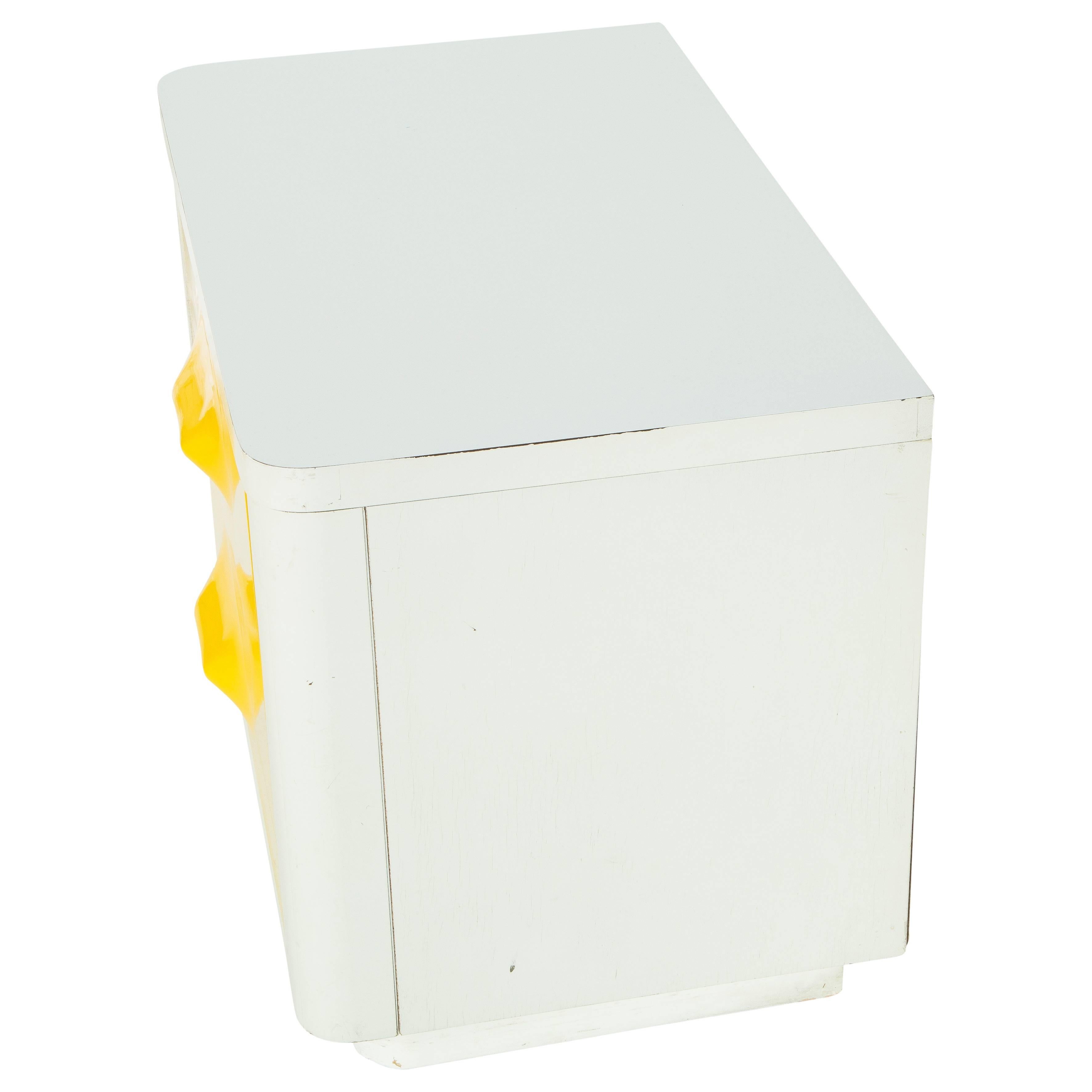 White and yellow Raymond Loewy nightstand in the style of Mod-Pop industrial design, circa 1970s. The white body of the credenza is lacquered wood, and the vibrant yellow drawers are molded plastic. Two drawers, in great condition inside and out. A