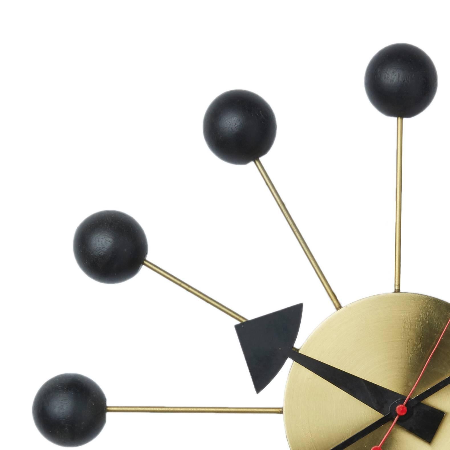 The Ball Clock, by George Nelson for Howard Miller, is one of his most iconic clock designs, originally designed and produced in the 1940s. 

This fine example, with 12 black balls on brass rods over a brass base, is in greater demand and harder