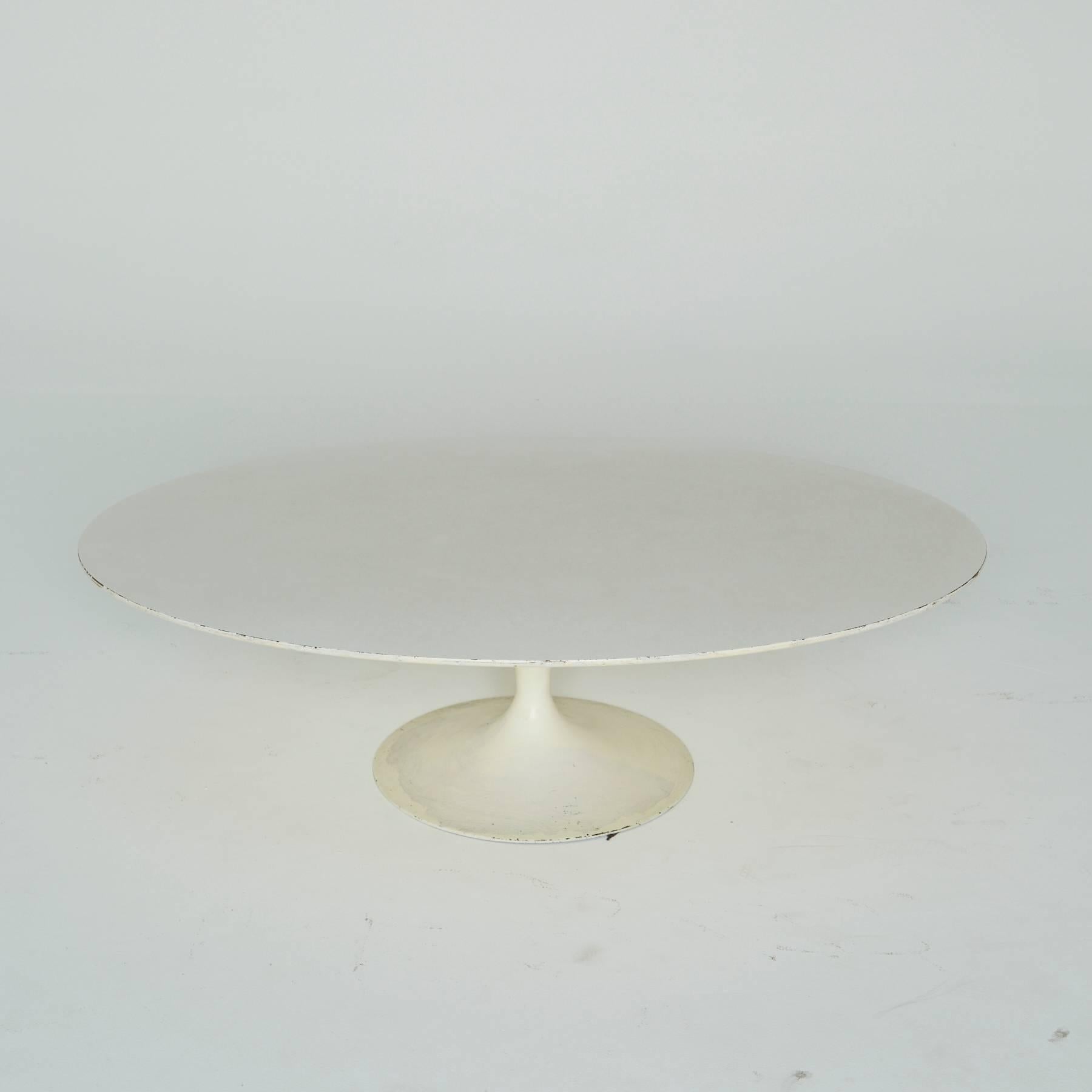 The white laminate oval tabletop is mounted on the famously curved cast iron pedestal base, creating the low, coffee table rendition of the widely recognized and adored tulip / pedestal table. Created by Eero Saarinen in 1957 for Knoll, the sinuous