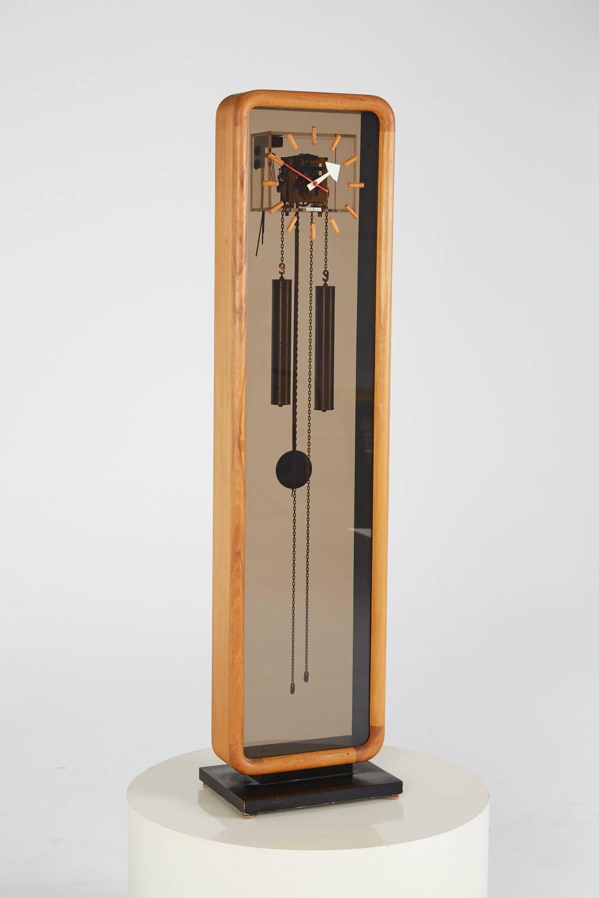 A Mid-Century Grandfather clock, designed by George Nelson for Howard Miller, Model No. 622. A wooden frame with rounded corners borders the smoked Lucite panes, displaying the inner workings of this supremely cool spin on a Classic home item.