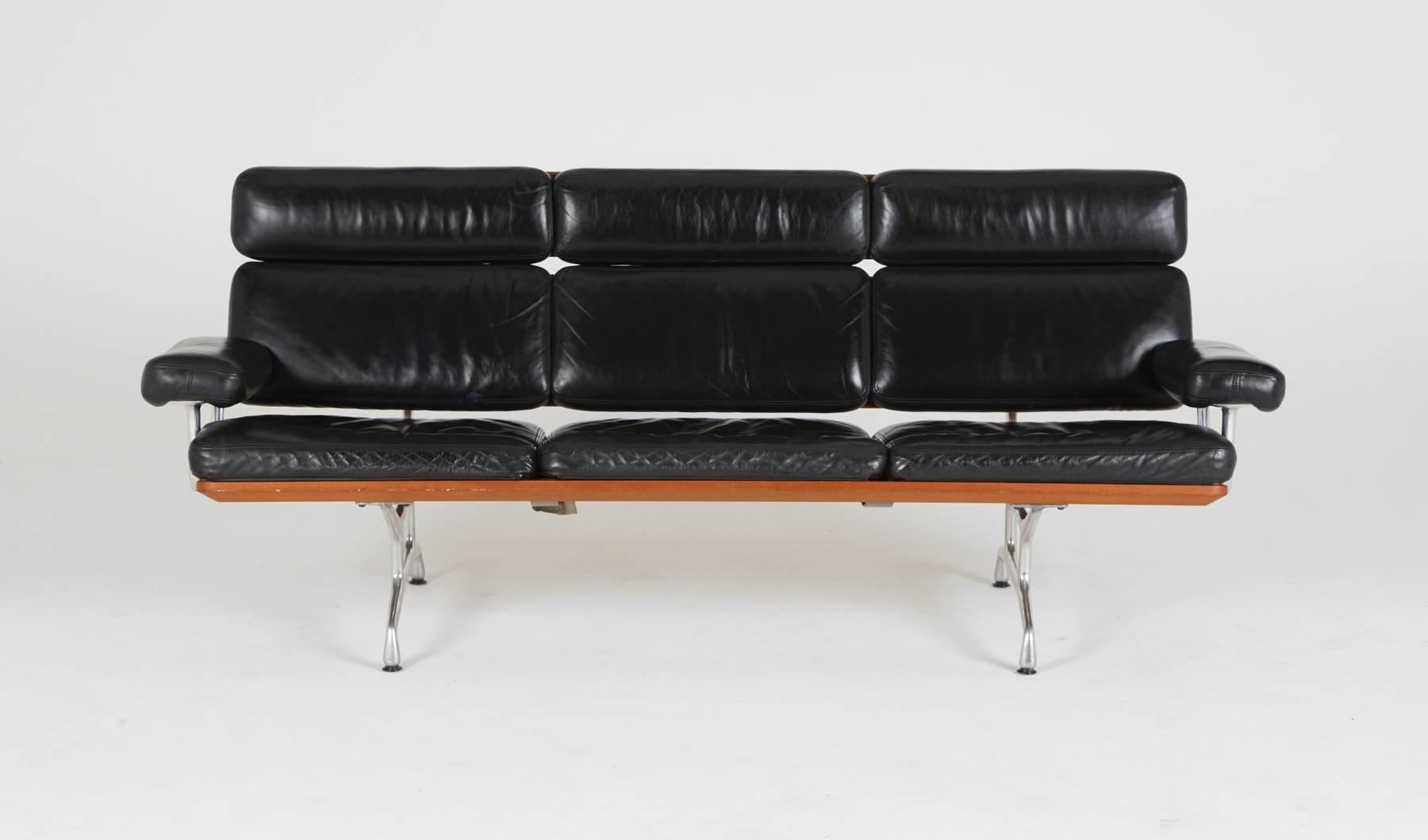 The Eames three-seat sofa, designed 1984, was Ray and Charles Eames's last design before Charles's death. It features two floating teak backrest panels across all three seats, while black leather upholsters the soft pad cushions. On the chrome
