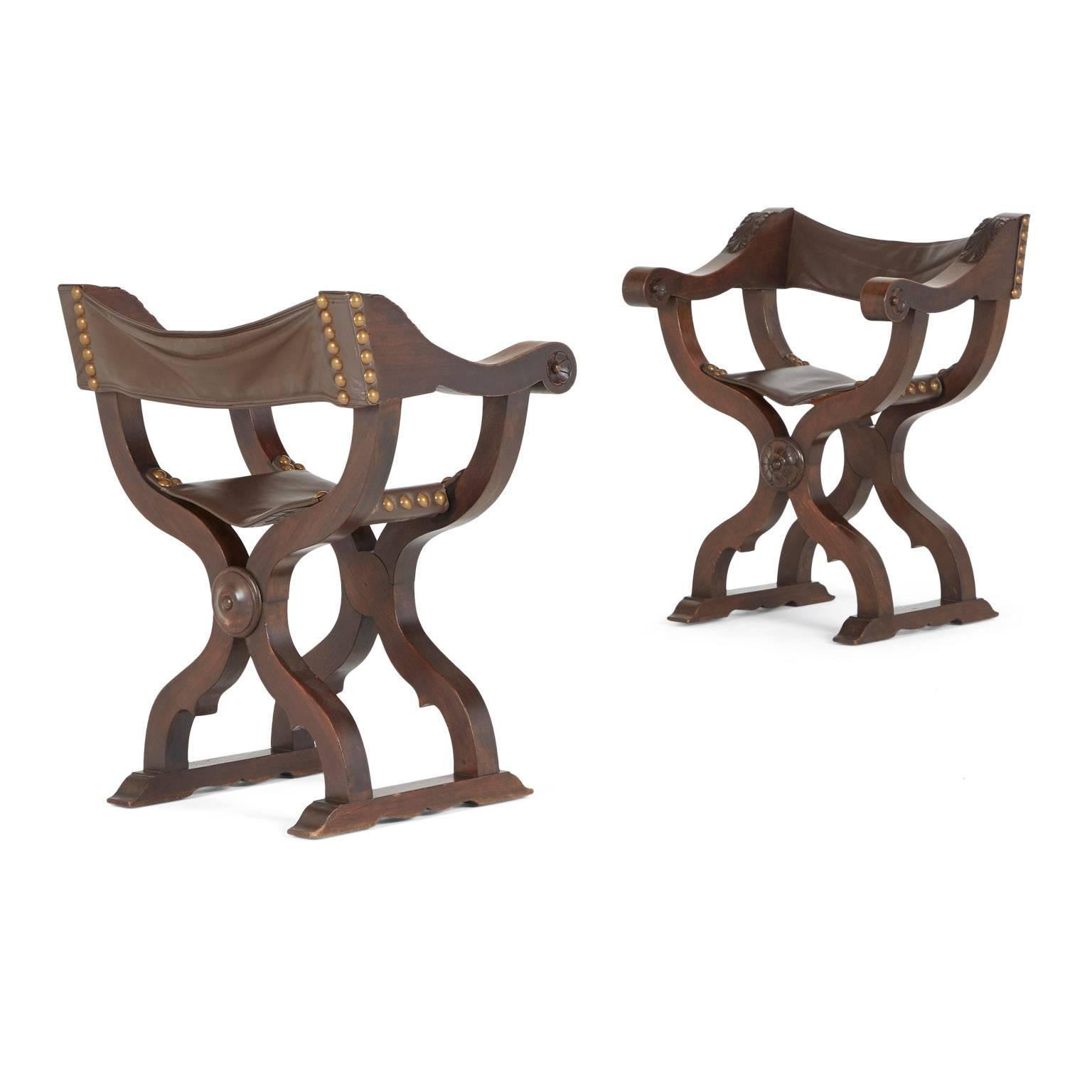 Pair of 19th century Italian hand-carved walnut Savonarola folding Campaign chairs, circa 1880. These chairs have been recently restored with rich brown leather and consist of scrolling arms, curule legs and sturdy brass nail-heads. The frame