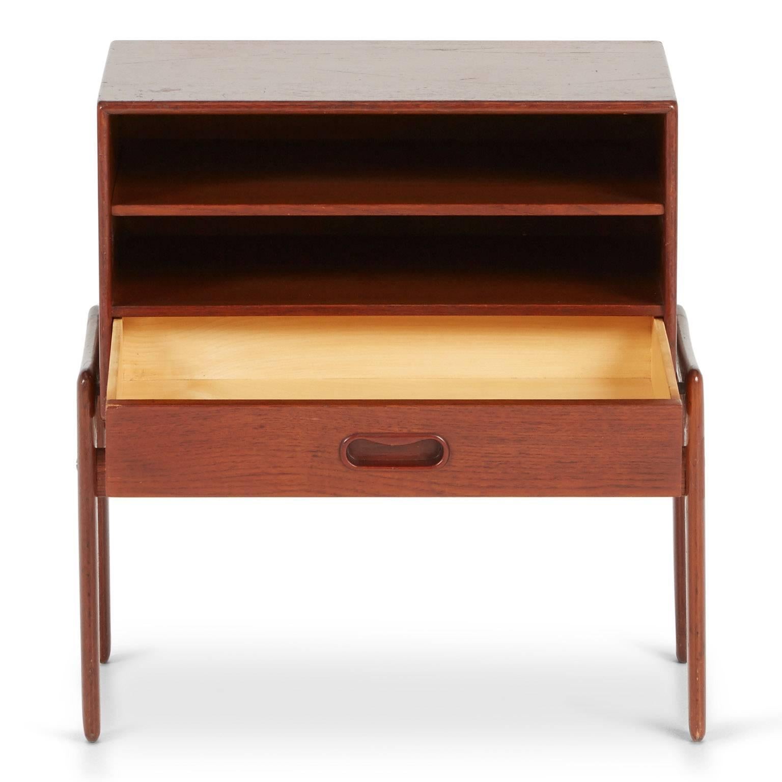 Sleek and compact, this Arne Vodder Danish Modern nightstand for Vamo Sonderborg is a testament of the application of traditional Danish craftsmanship expressed in Mid-Century design. Comprised of rich toned teak this piece offers an open shelf and