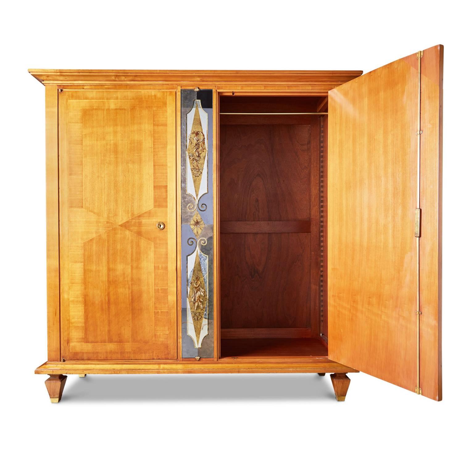 Spectacular Art Deco fruitwood armoire attributed to French designer and sculptor André Arbus. Featuring stunning gold leaf verre églomisé detail on the central panel which depicts classical figures surrounded by delicate borders and embellishments.