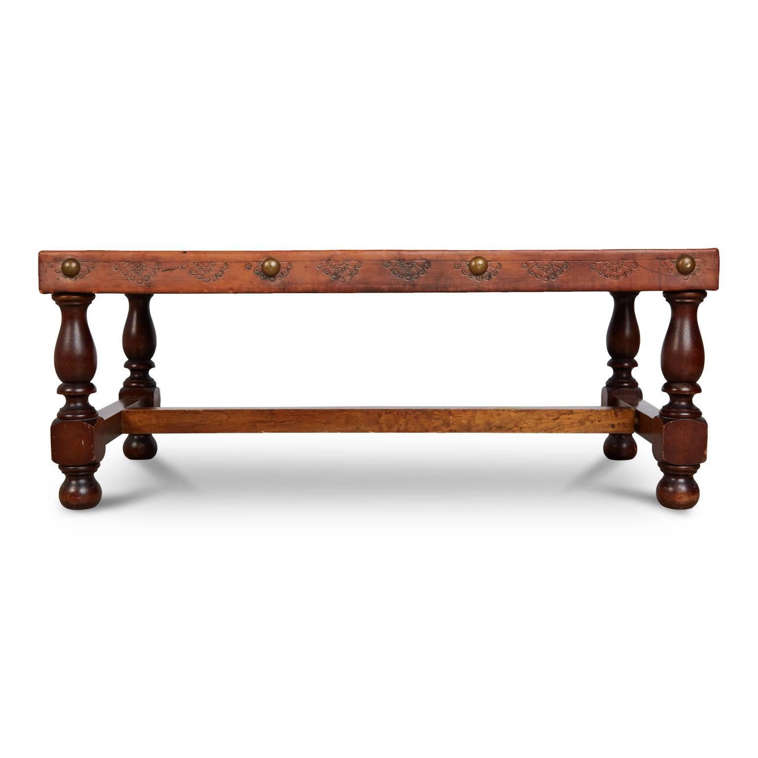 Beautifully hand tooled Peruvian bench or coffee table (you can use for either) depicting a South American pastoral scene. Fabricated from a walnut frame with turned wood legs, the top is wrapped in leather and illustrated with embossed figures on a