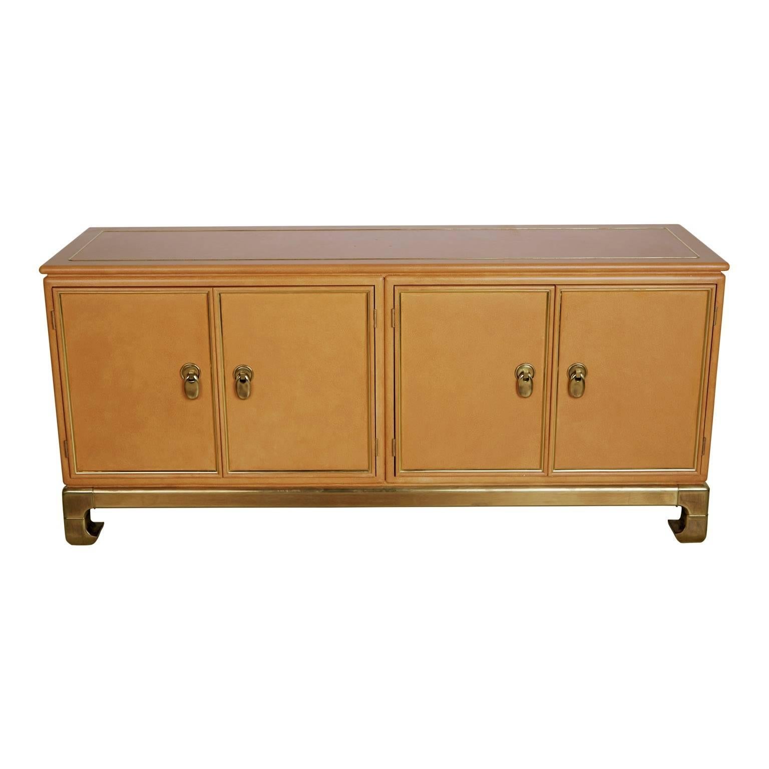 Stunning hefty and substantial custom ordered credenza from Mastercraft. This gorgeous piece features a lacquered faux ostrich skin top over wood with embossed patterned border, sturdy luminescent on-trend brass base and Asian inspired hardware.