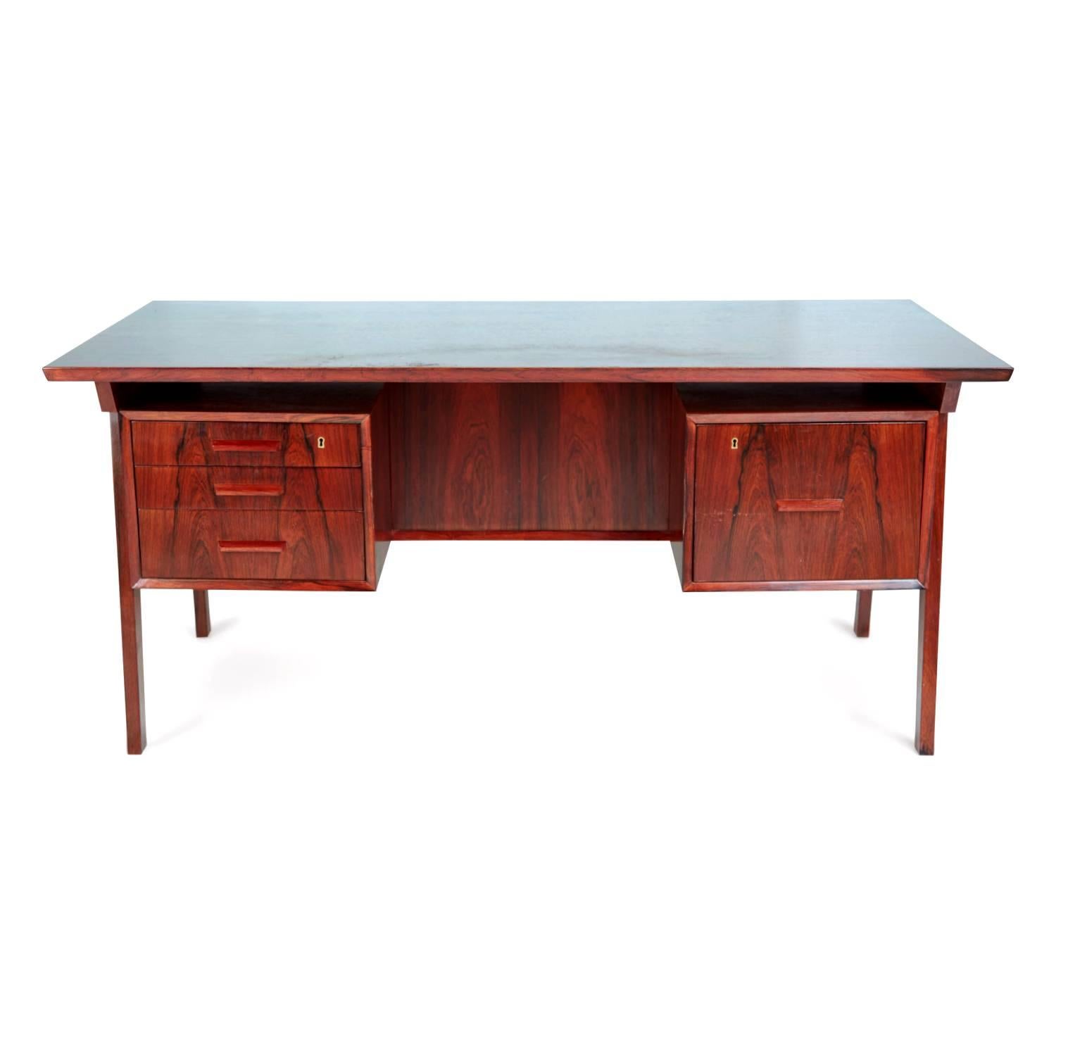 Gorgeous desk that has been expertly crafted from rosewood with a stunning grain. This desk features a broad Brazilian rosewood top with three paper drawers on one side, of which the top is lockable, and one file drawer on the right, also lockable.