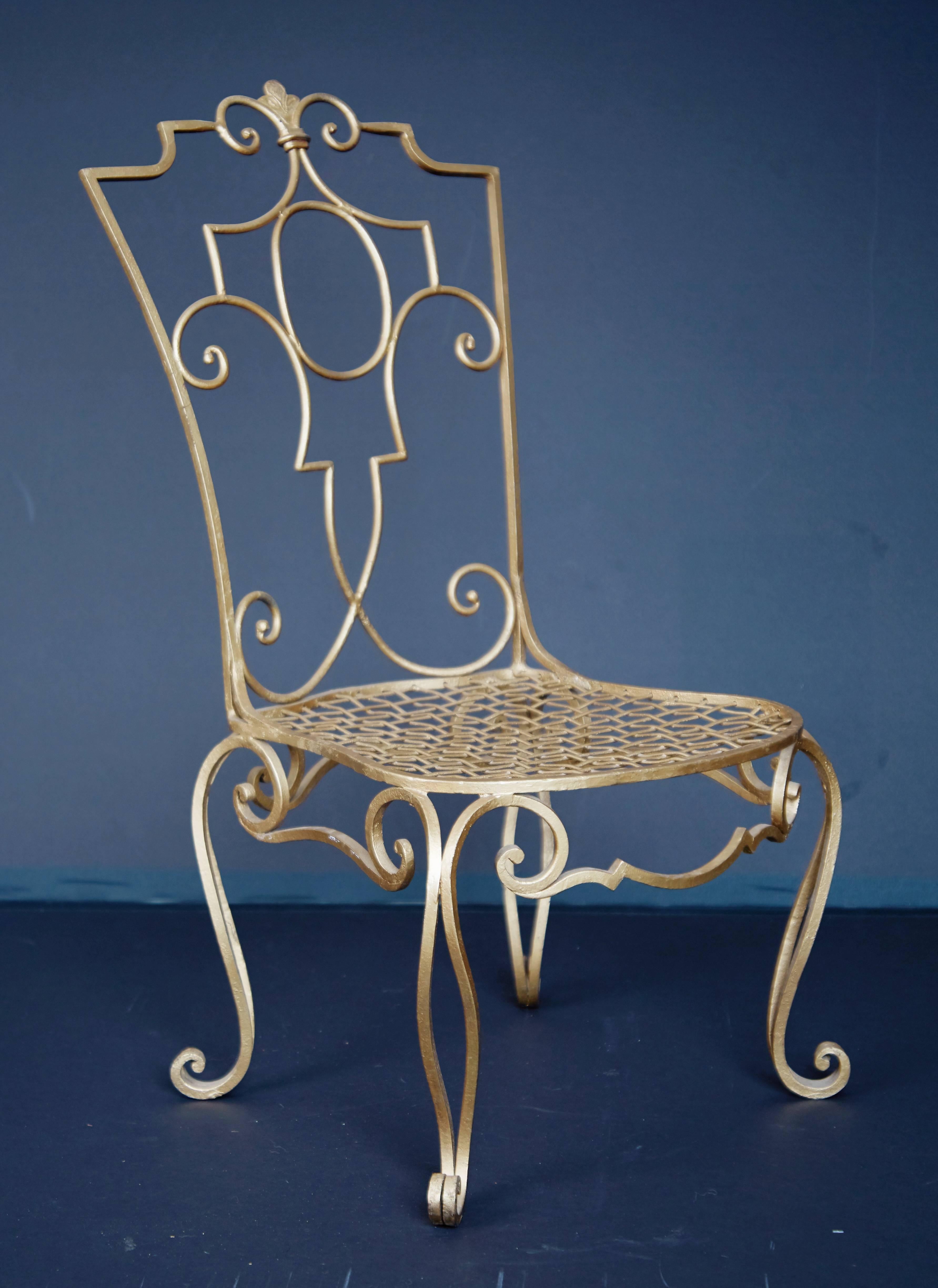 Lustrous wrought iron low side chair by French designer Jean Charles Moreux. Featuring curvaceous use of hammered wrought iron on the frame with curled detail on the feet, back upright and seat rail. This chair has been painted in a gleaming gold