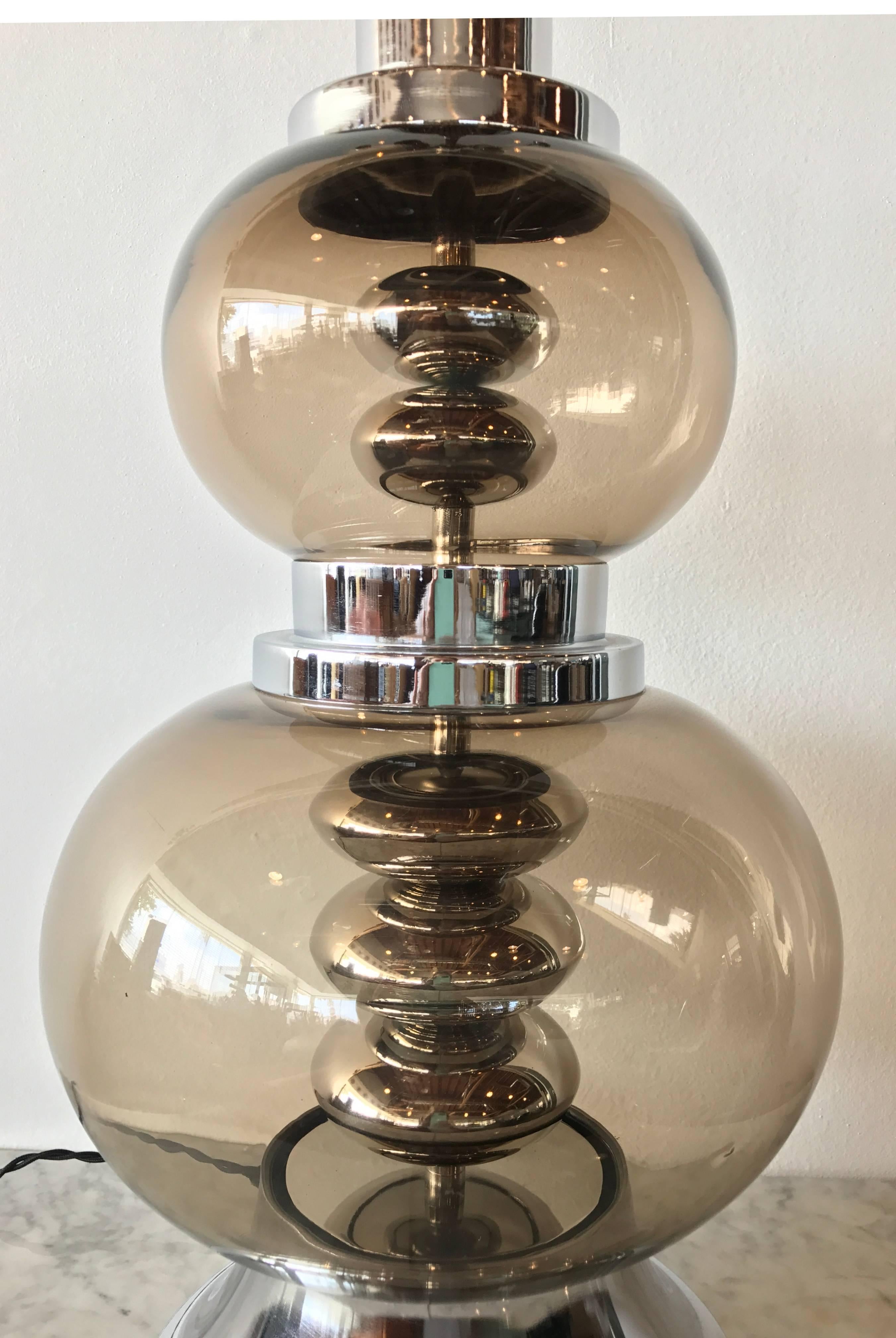 Seductively curvaceous Italian smoked glass table lamp, circa 1970. The soft gray glass with a very subtle amber undertone is punctuated with polished chrome base, middle and stem as well as polished chrome ellipsoids stacked on top of one another