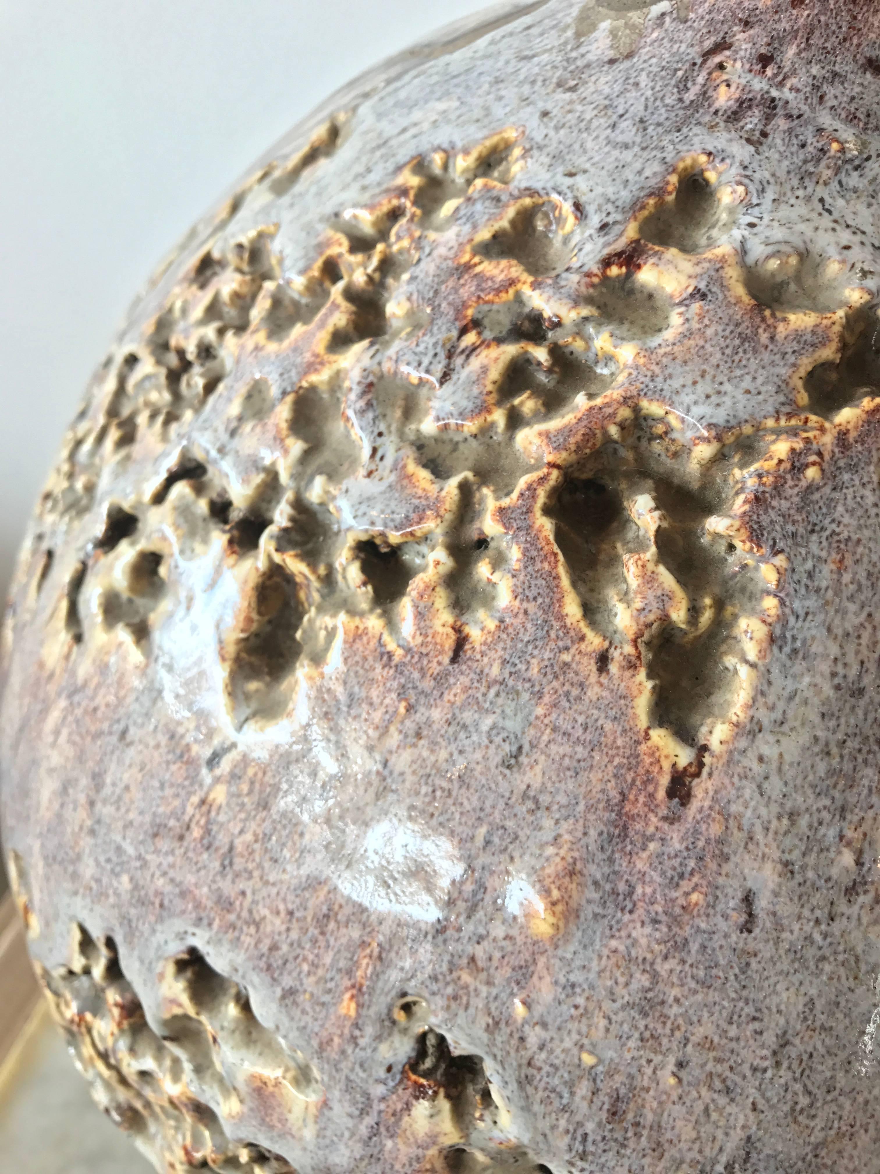 Wonderfully textured spherical ceramic lamp featuring clusters of organically formed pockets and chambers across the surface as well as variation in the glaze density. The focal color is a soft mauve with shades of lavender, lilac, charcoal gray,