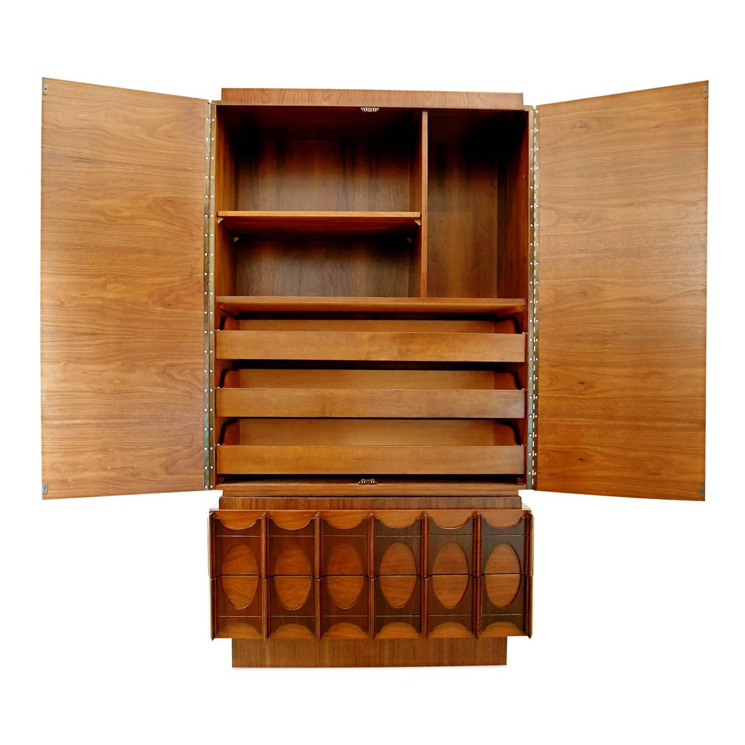 Substantial sized chest on chest in the style of Kent Coffey's Brasilia collection. This chifferobe is fabricated from walnut and has been newly refinished in two shades of rich brown. The body of this modern highboy has been finished with a lighter