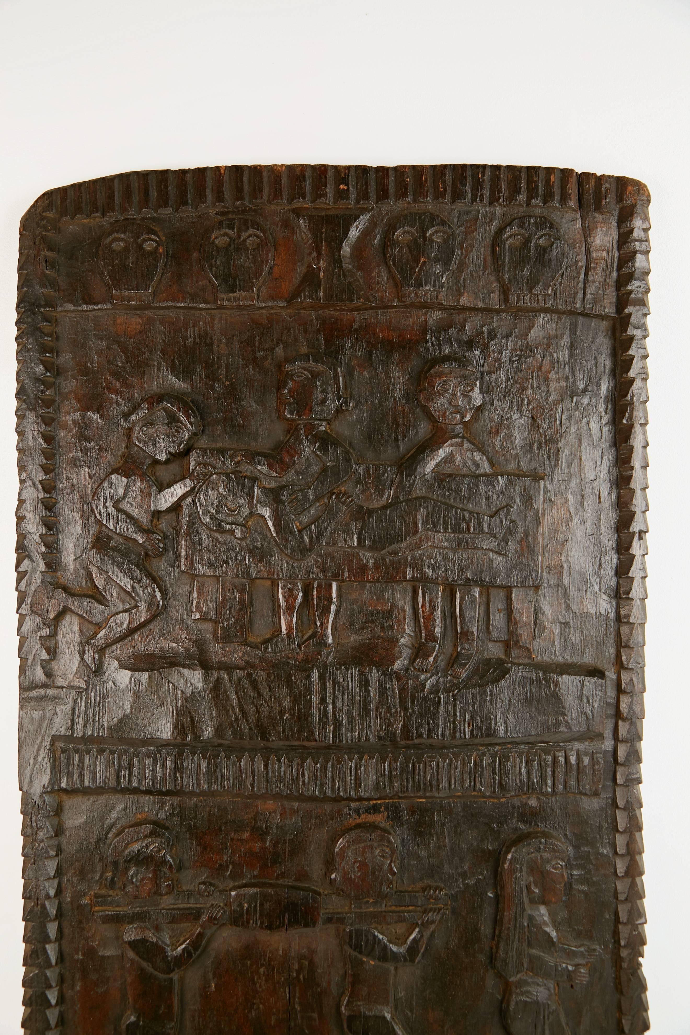 Large decorative African carved granary door featuring figures in various pursuits carved in the traditional manner by tribal artisans. This door has a wire affixed to the back for hanging on the wall. 

This creative piece can be used as wall art