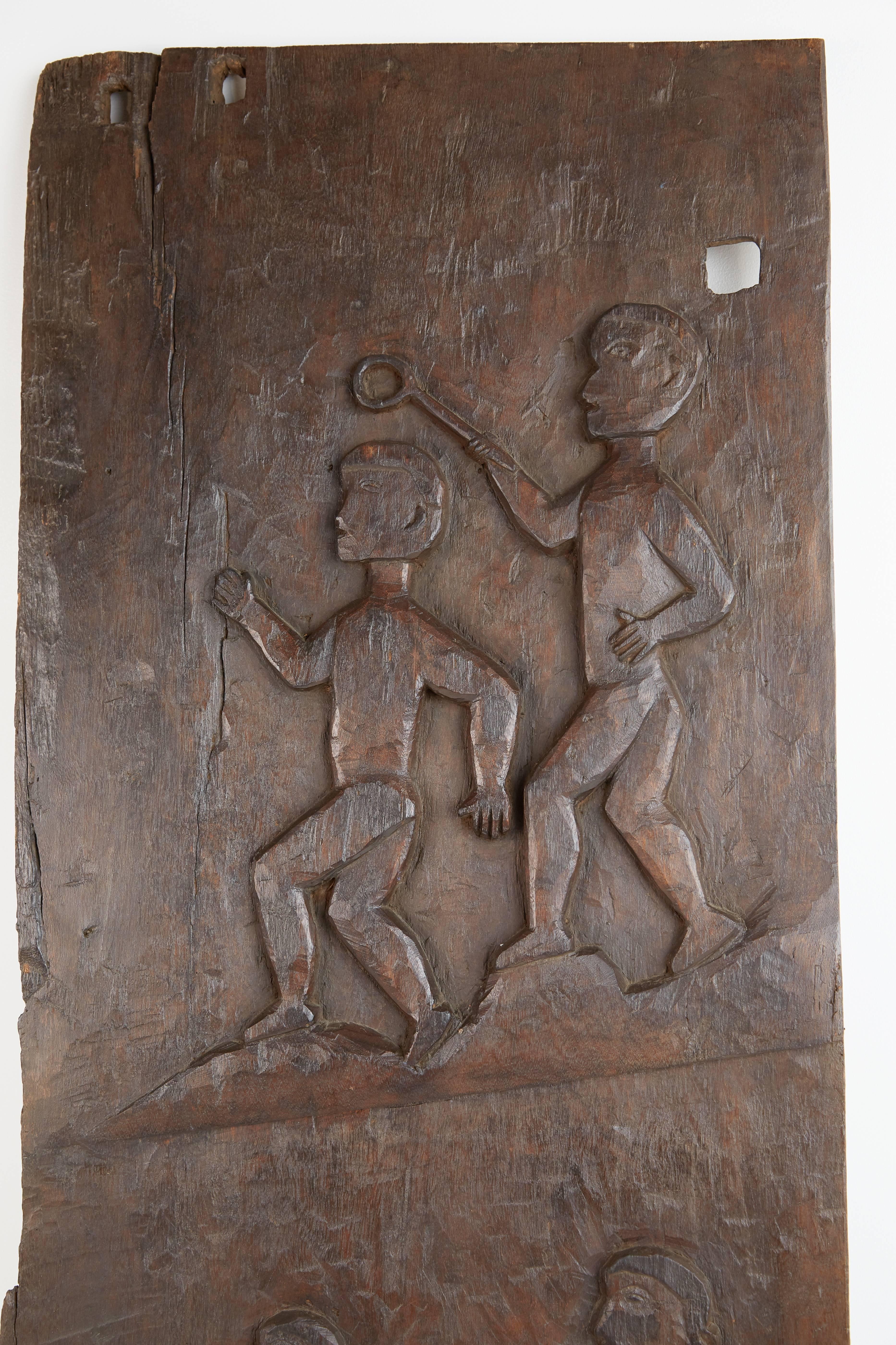 Decorative African carved large granary door featuring figures holding various tools carved in the traditional manner by tribal artisans. At one end the door can be mounted using two holes and it also has a wire affixed to the back for hanging on
