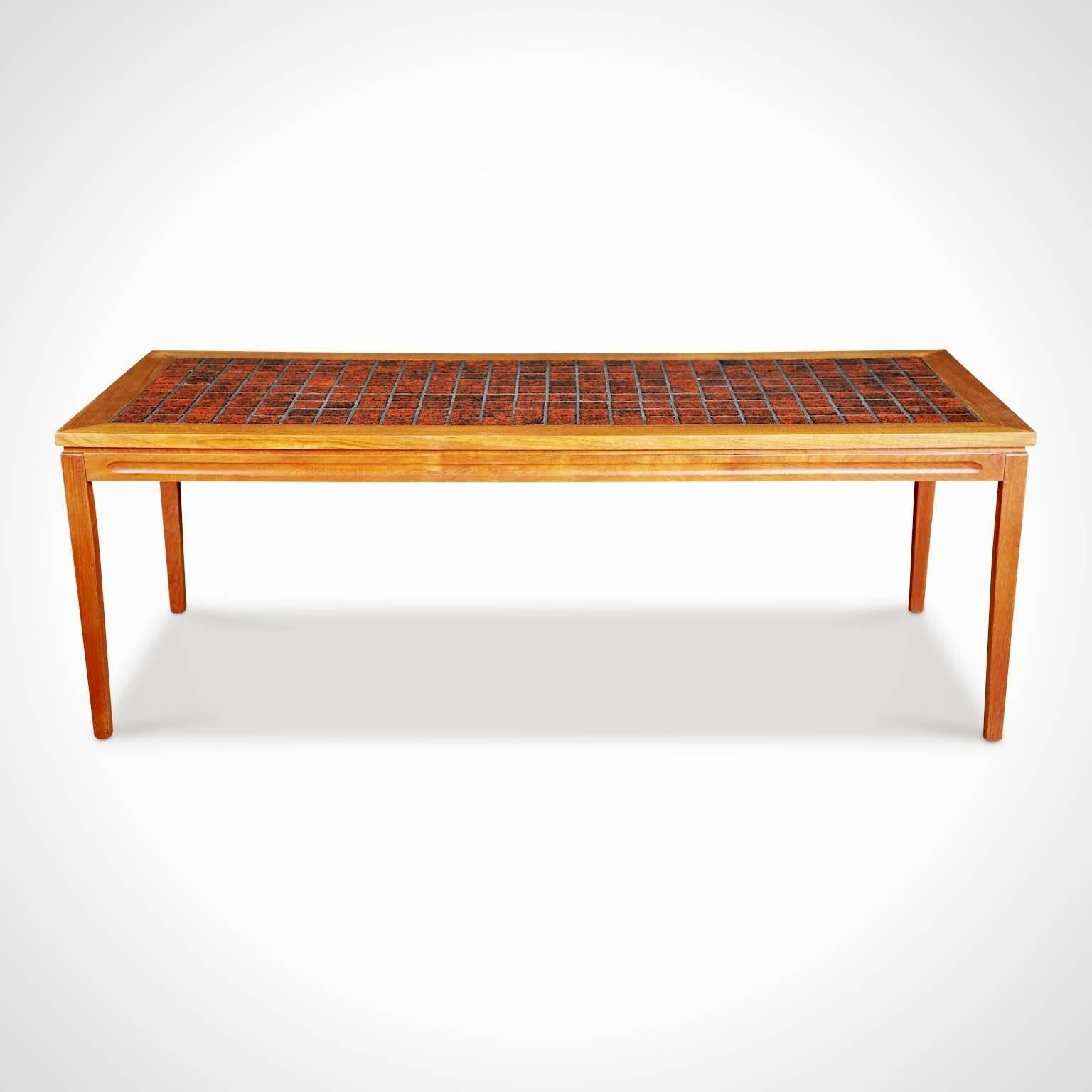 Danish midcentury teak coffee table, circa 1960 in the style of David Rosen for Nordiska Kompaniet. Featuring a rectangular top decorated with rust colored ceramic tiles of varying shades in a uniform pattern that are punctuated with flecks of