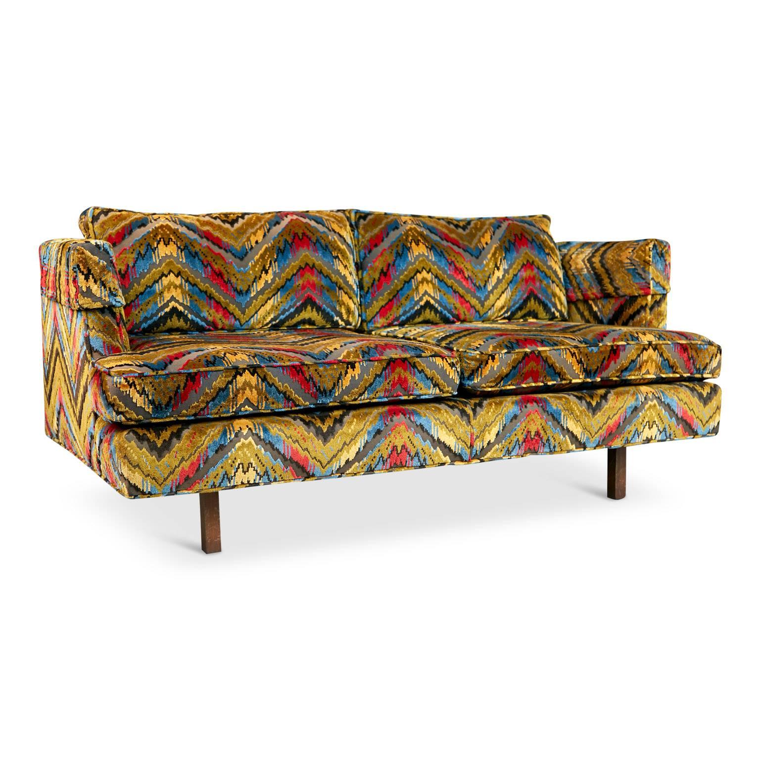 Why settle for one eye-catching sofa when you can have a pair? This set of two Edward Wormley style settees make a stunning duo which would impact any space. Both are upholstered in a quality cut velvet with a vibrant chevron pattern which