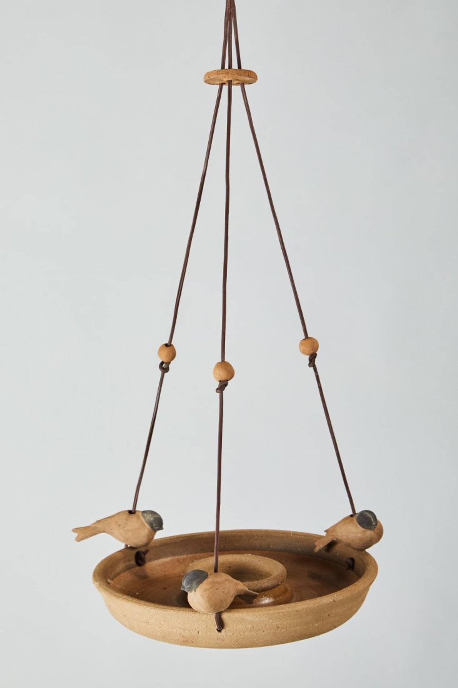 An expertly crafted bird feeder or bath by Stan Bitters for Hans Sumpf. Comprising of a circular ceramic dish with a clear glazed interior and three intricately formed finch-like clay birds that perch on the rim. The vessel is suspended by a sturdy