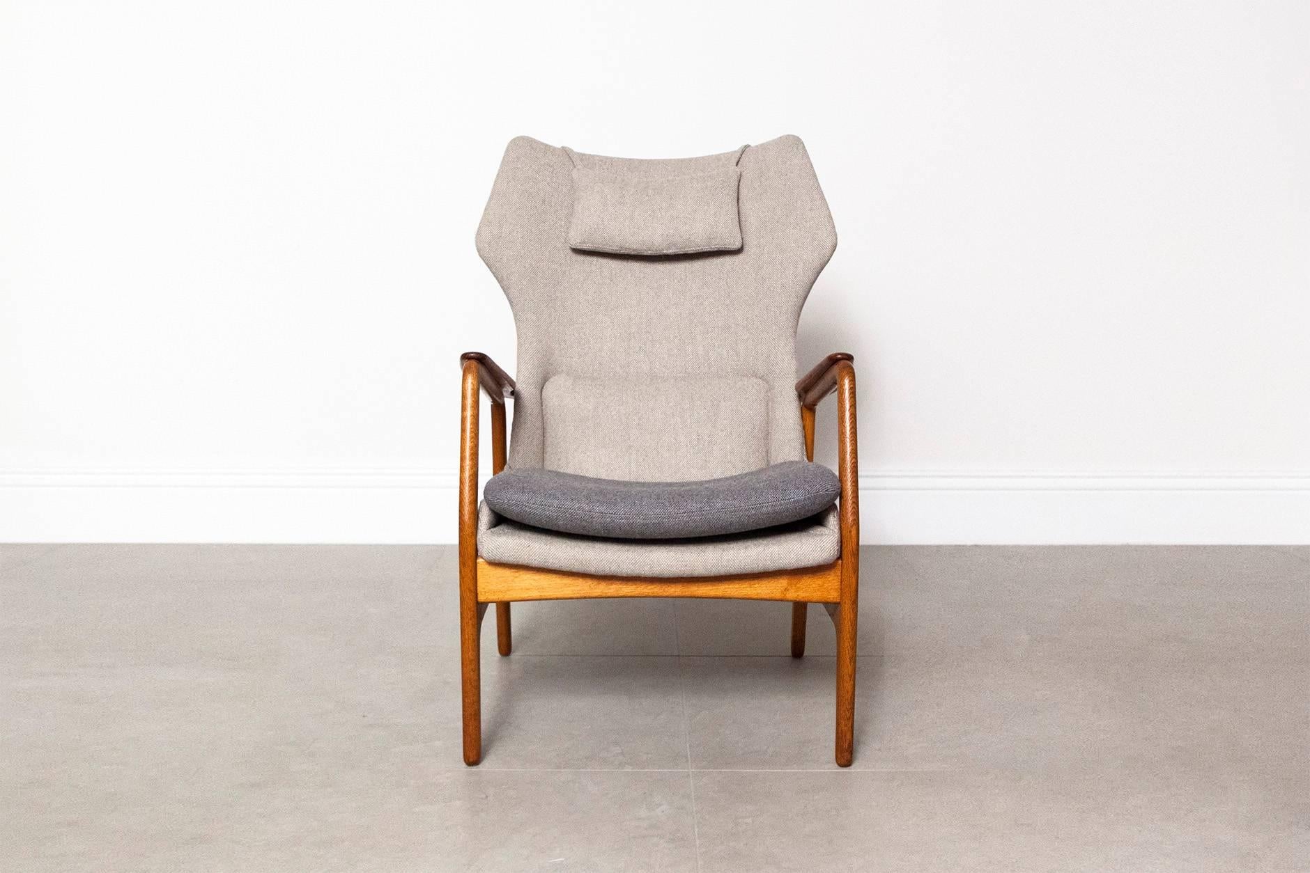 Danish designed wing back chair for Dutch manufacturer Bovenkamp, circa 1960, courtesy of Aksel Bender Madsen. The elegantly curved teak armrest sits on top of a golden oak frame  and has been reupholstered in Bute grey tweed with contrasting seat