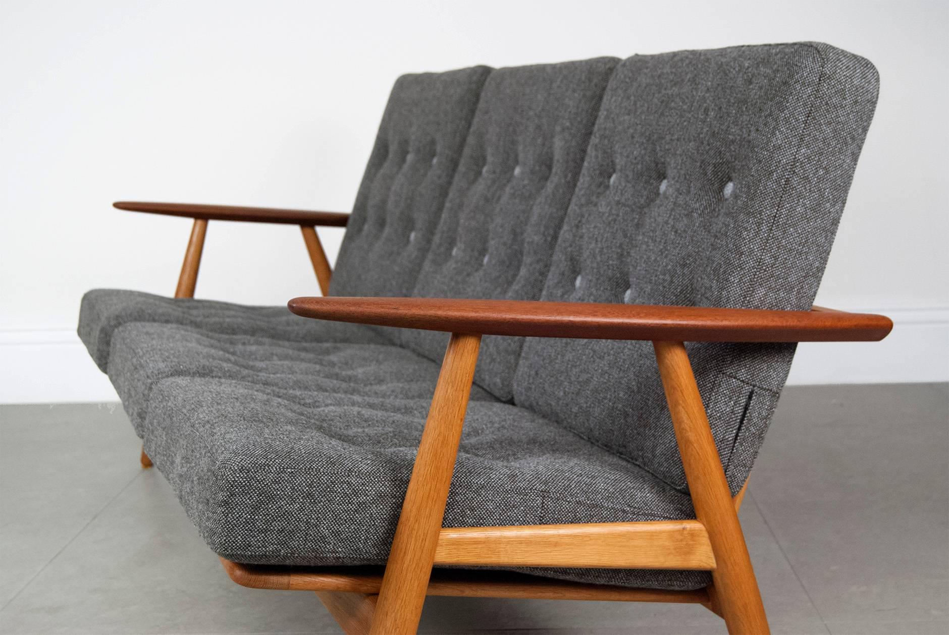 Hans J. Wegner.

GE-240 'Cigar' sofa, 1955.

Three-seat sofa with oak frame and contrasting teak armrests. Original sprung cushions recovered in Kvadrat Hallingdal wool fabric with contrasting buttons. Produced by GETAMA, Denmark.
