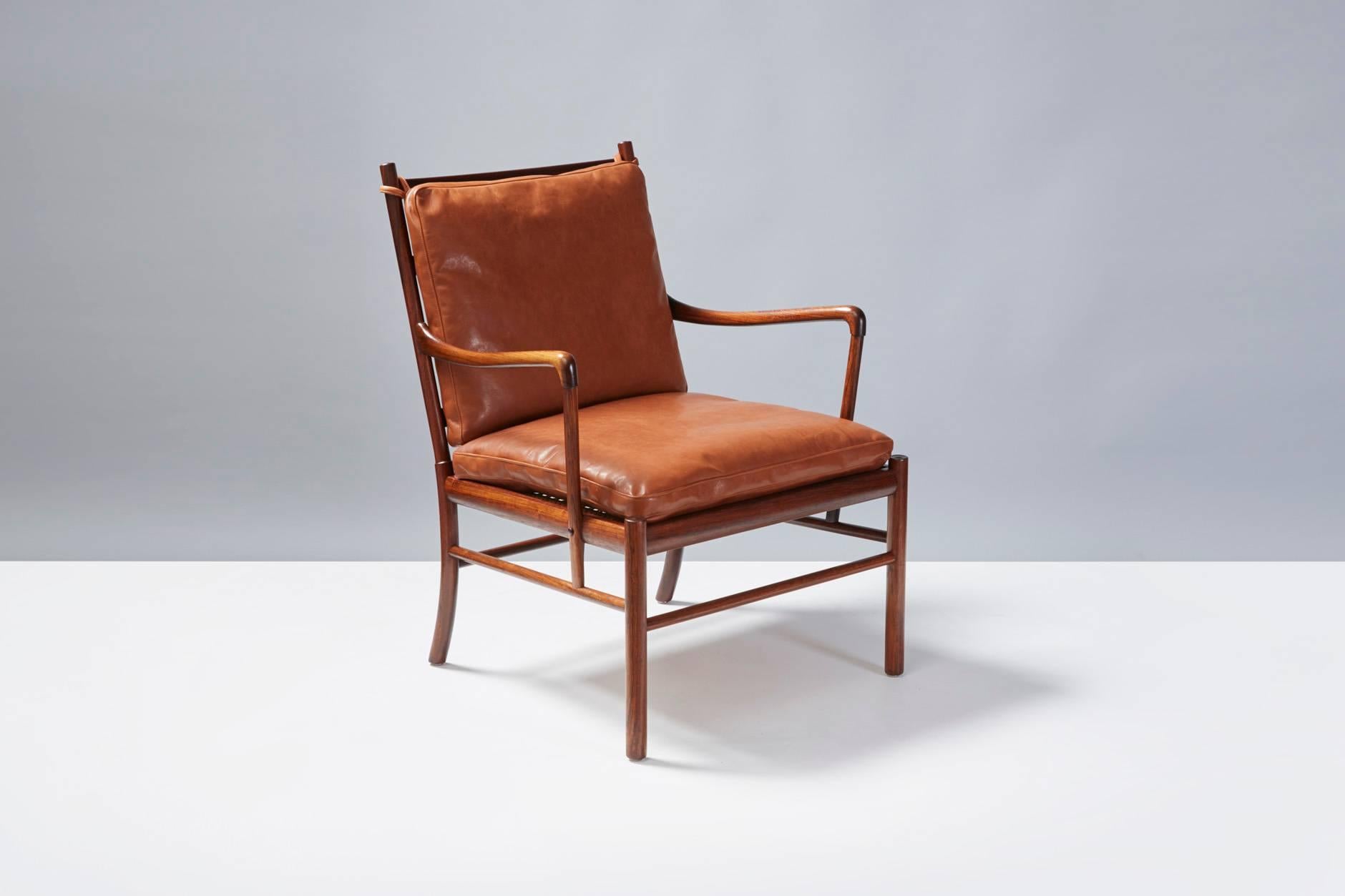 One of Danish master Ole Wanscher's finest creations. The colonial chair was inspired by British and French 19th century furniture styles. This rosewood armchair has a removable woven cane seat. The loose cushions are covered in new aniline brown