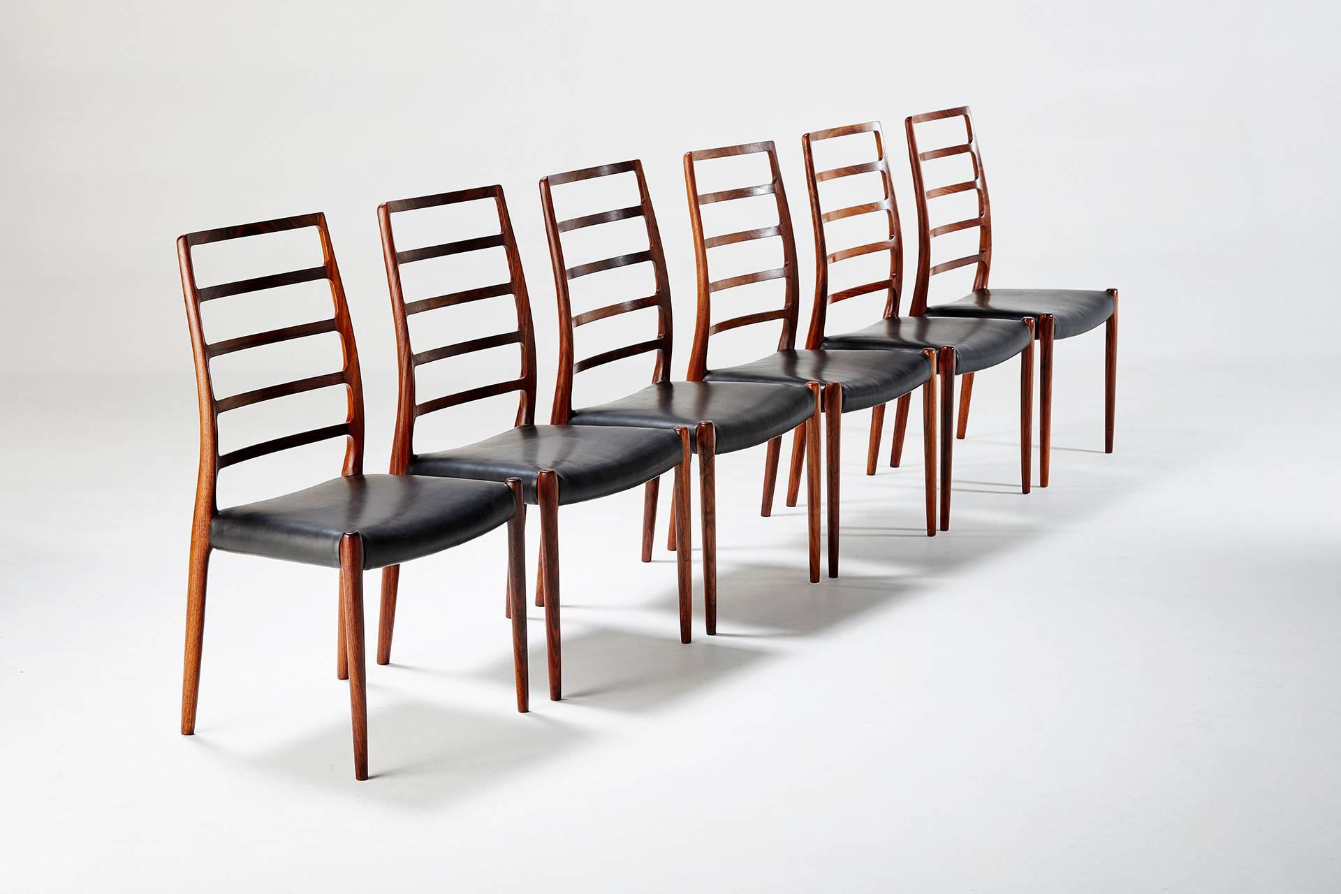 Produced by J.L. Moller Mobelfabrik. Made from solid rosewood with luxurious, exotic grain. Seats reupholstered in black aniline leather. Rarely seen set.