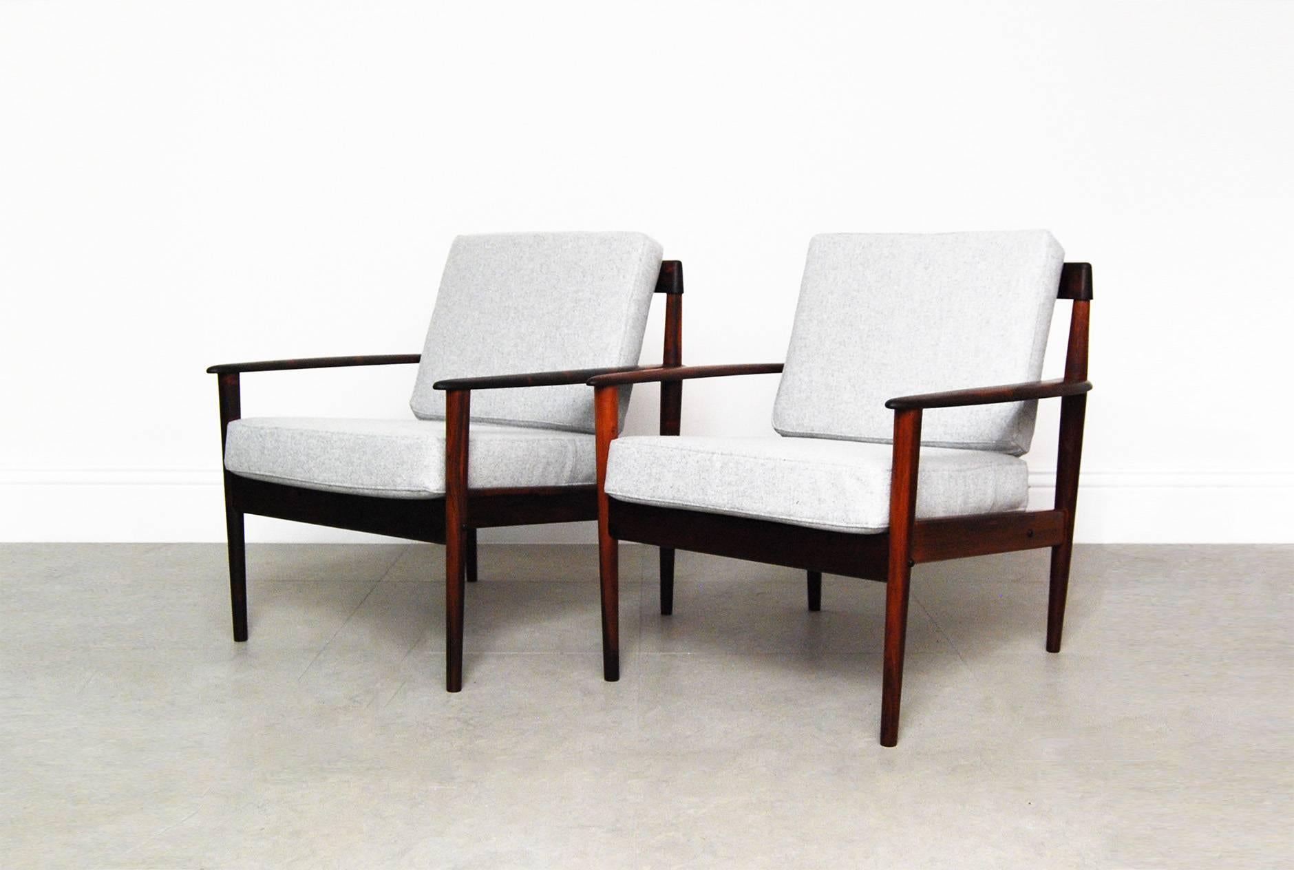 A pair of beautiful armchairs and matching ottoman designed by Grete Jalk for Poul Jeppesen, Denmark, circa 1956. These examples come in solid Brazilian rosewood with a particularly unusual, exotic grain. Danish furniture control badge and maker's