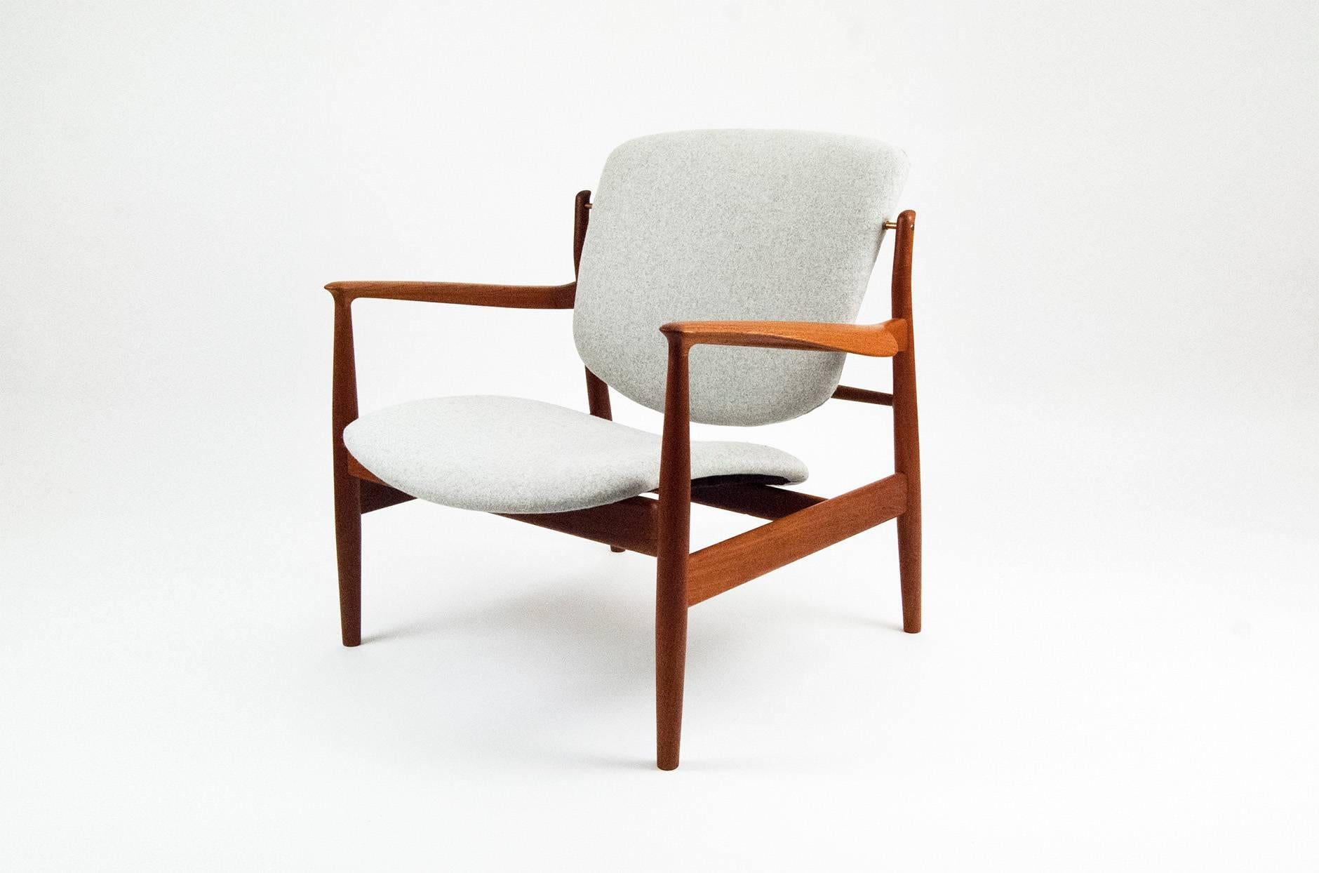 A rare design from Danish master Finn Juhl, the most collectable of all the Danish modern designers. The 136 chair features teak frame, suspended back and seat pads and exposed brass joints. The seat and back have been reupholstered using light grey