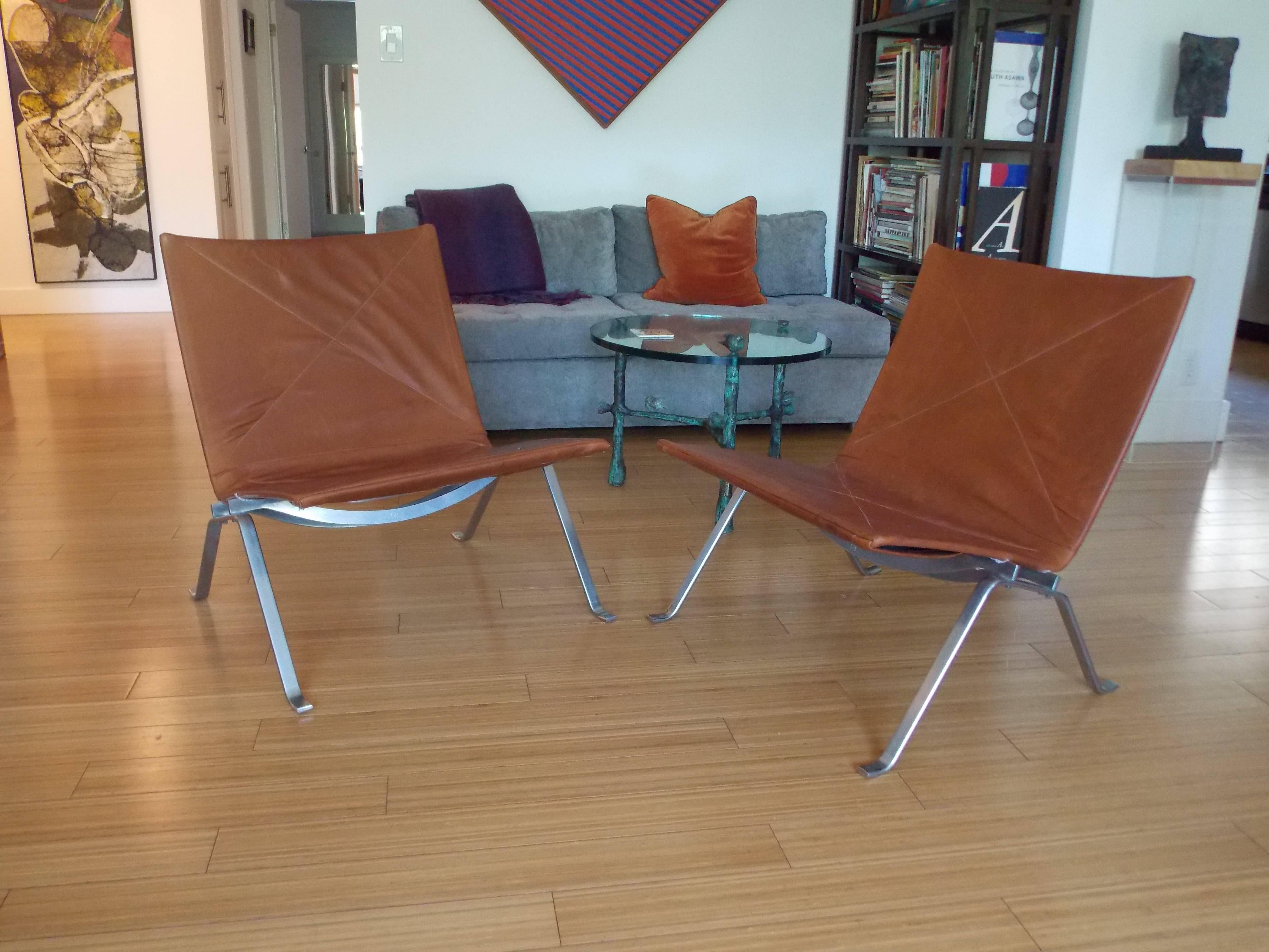 A handsome pair of modernist designs. 
The leather shows a bit of distress with a nice burnt sienna color.
The base is made of chrome plated steel.
One of the bases has some plating loss at the feet and pitting.
These chairs are still sturdy and