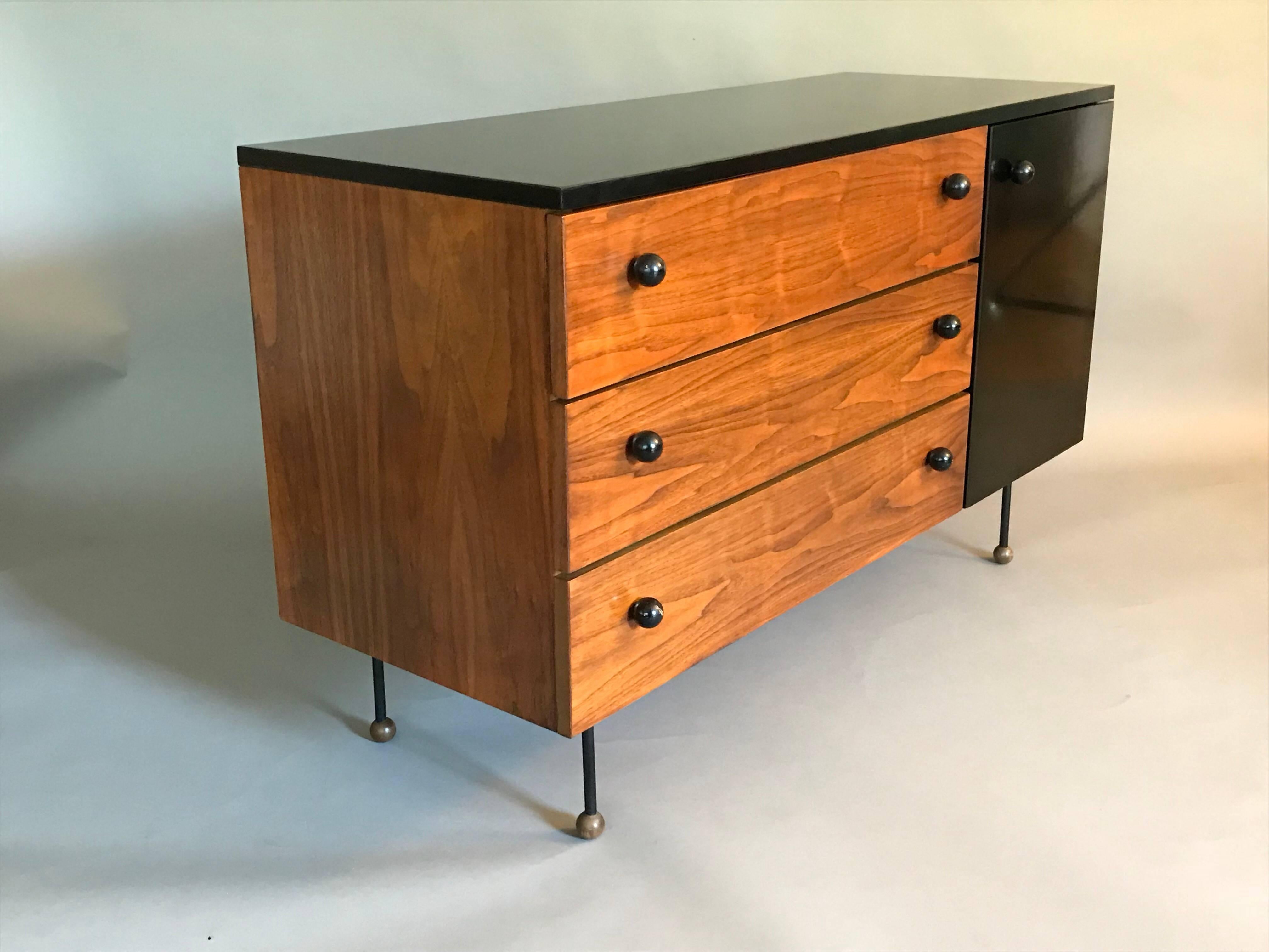 A rare and early California Modern design.
Made of plywood with walnut veneer, laminate top and door with iron and wood ball feet, original screws and knobs. 
The wood has been lightly refinished without taking away from its' historical integrity.