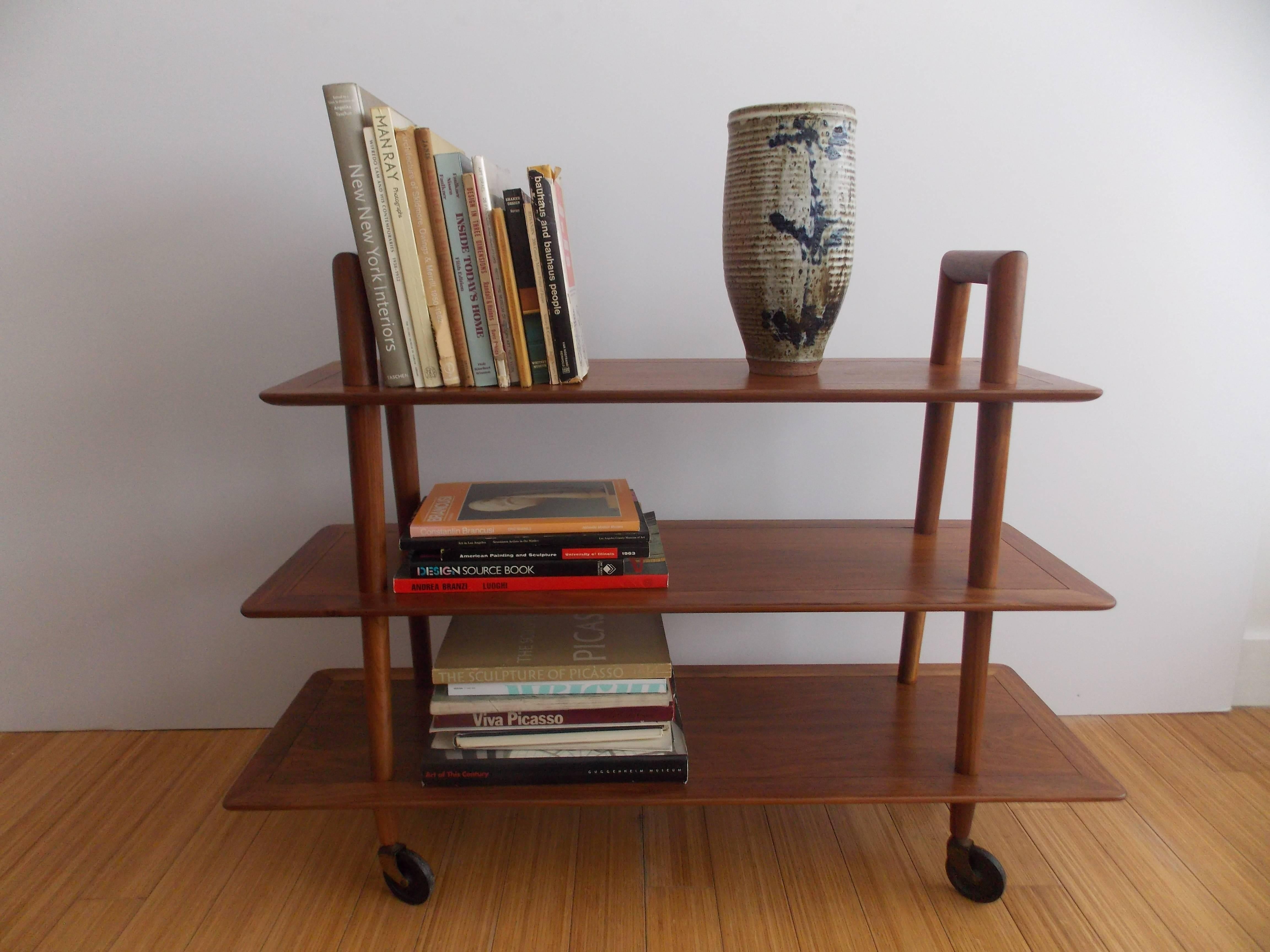 An nice modernist design.
Simple with elegant lines.
Made of walnut with hard plastic wheels.
The wood has been refinished to its natural grain.
The wheels show ware / patina.
No damage.
 