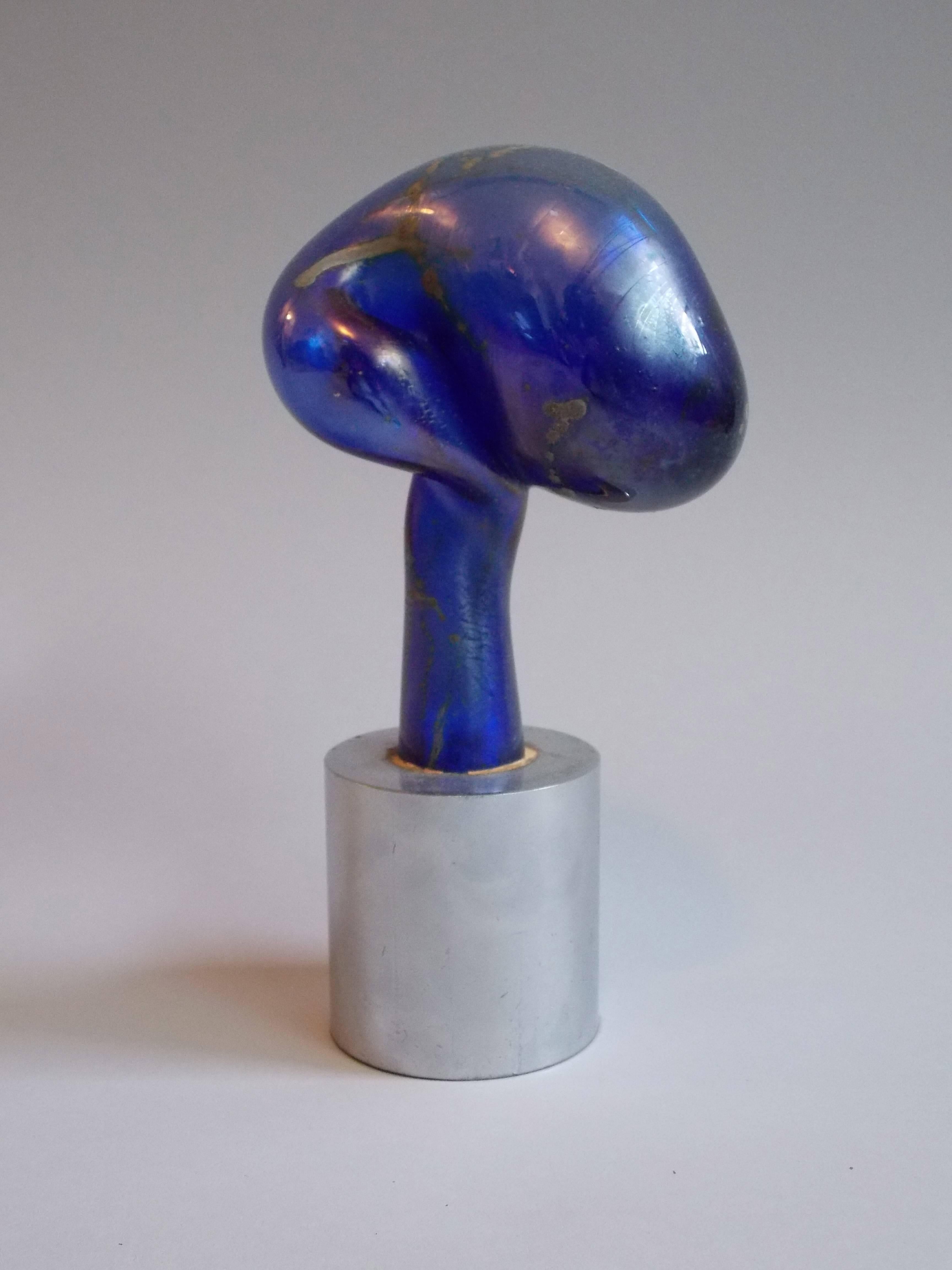 1932-2013.
A well listed artist who was a professor, author and potter.
This is rare piece of art by him.
Made of handblown glass with a beautiful blue hue, embedded onto a solid steel base.
It is stamped on the base 