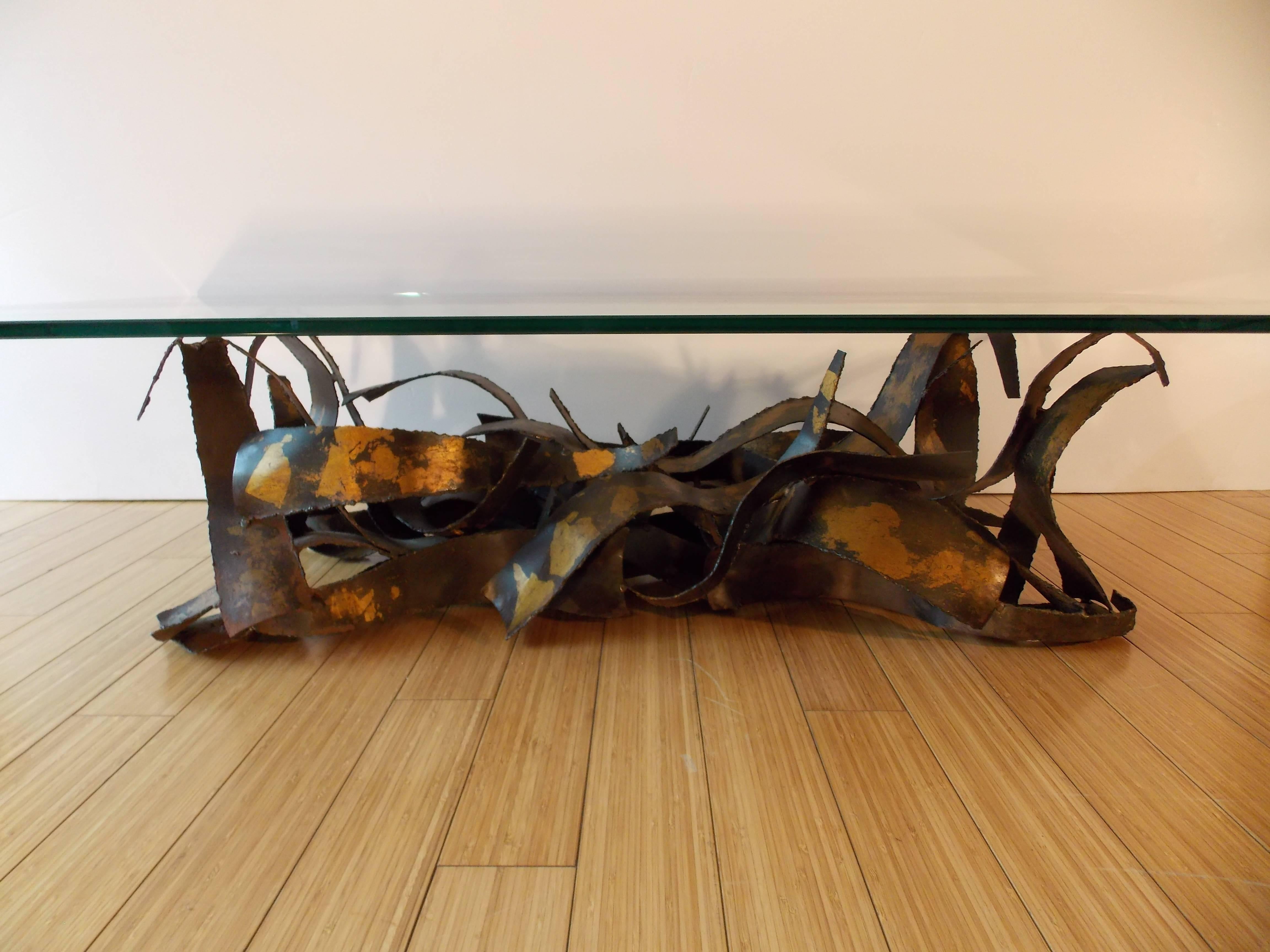 This table appears to be a one-off, custom piece.
It came from an old estate in mid-city Los Angeles.
Quality made of sculpted torch cut sheet steel with patina and gold leafing with original glass top.
There are no chips on the glass, but has one