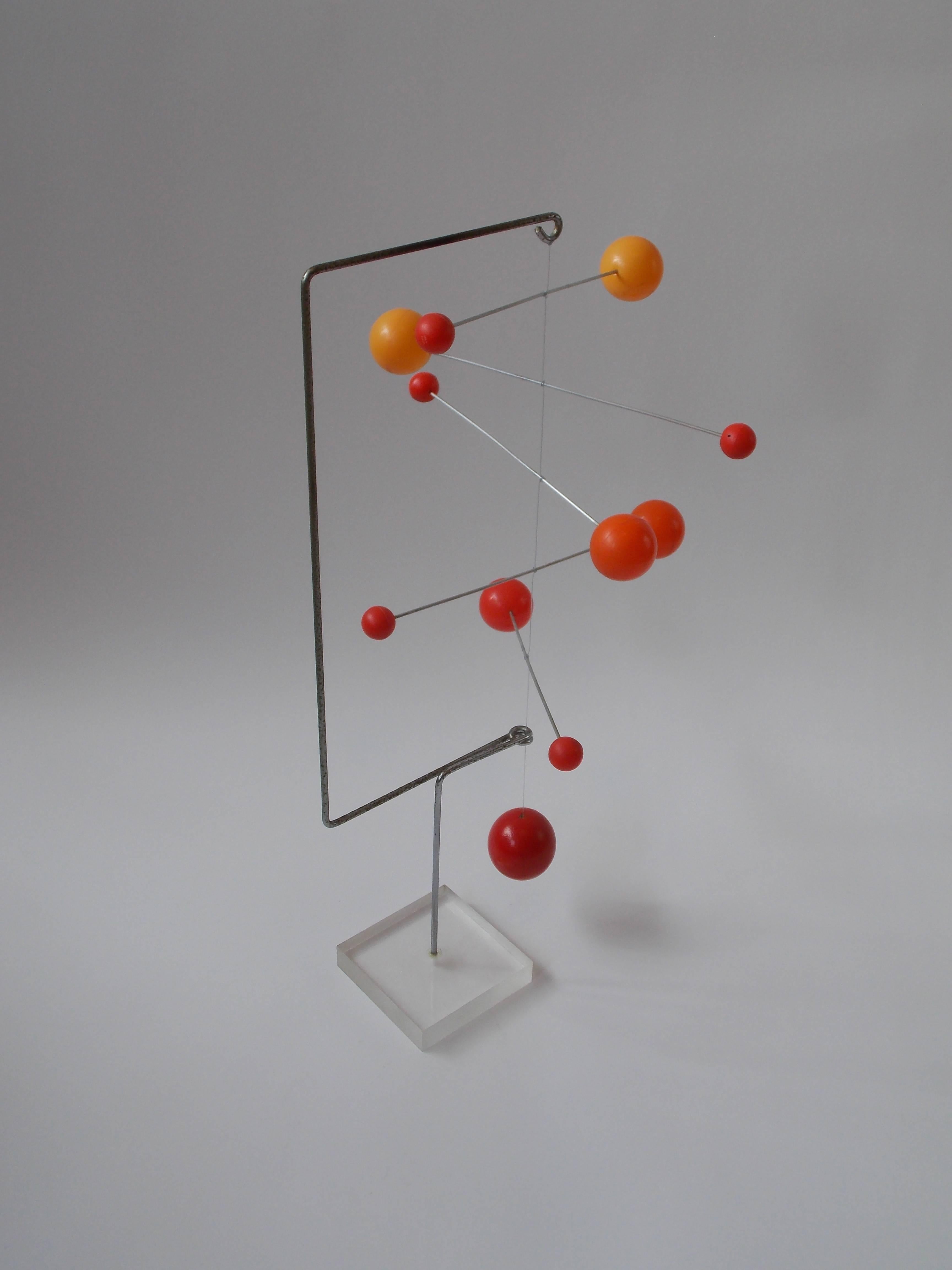 A fun design. Made of colored plastic spheres on aluminum rods and red painted solid wood sphere at the bottom with wire on a steel arm connected to a Lucite base. It's in the original vintage condition showing ware / patina, no damage. The spheres