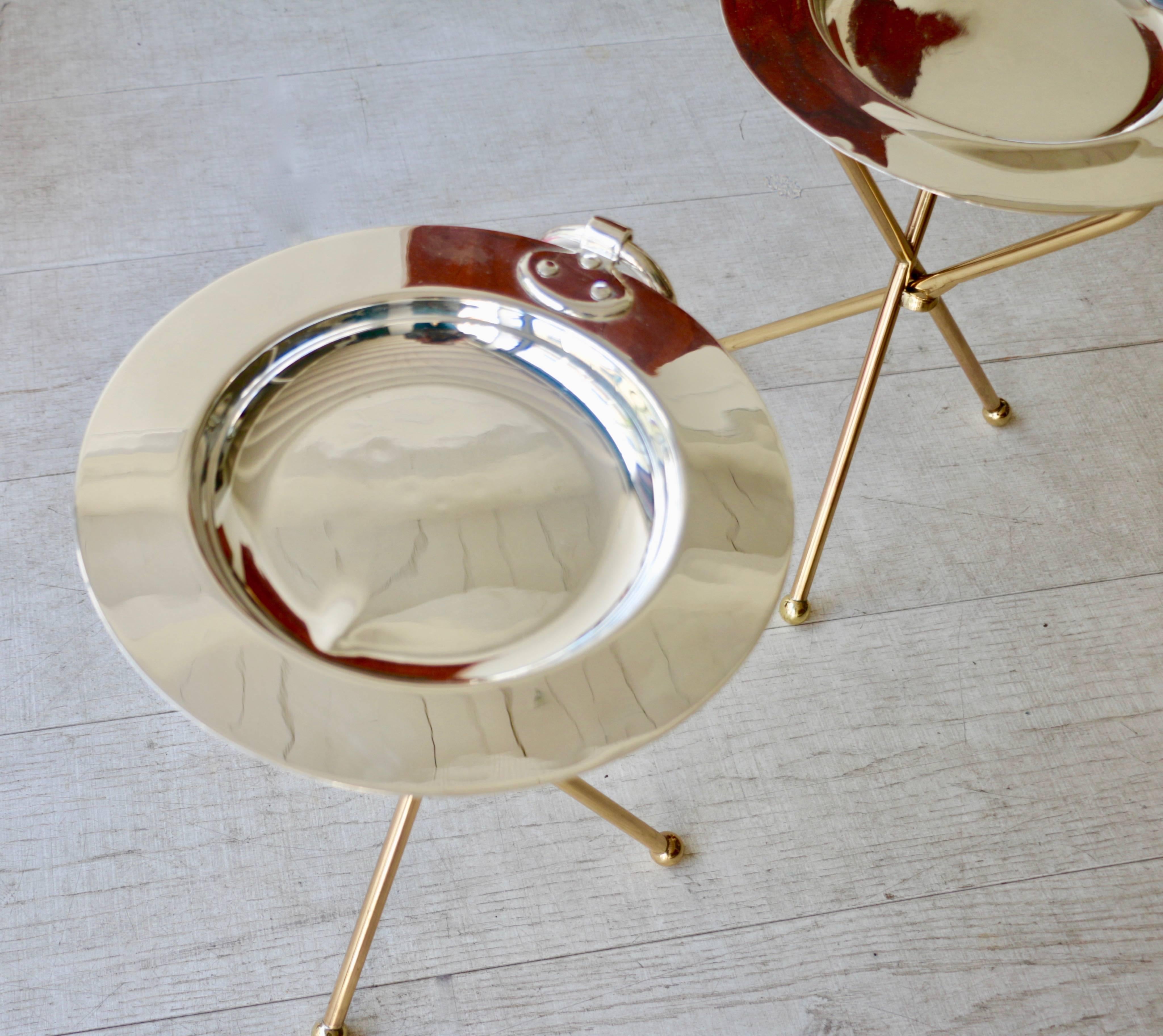 1980s, pair of small folding gueridons. The tray is made of silvered metal and the feet are in brass. A large ring allows to transport them. One of the trays should be re-silvered. Signature.