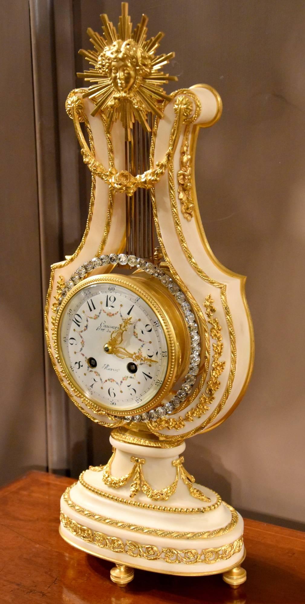 A good French white marble and ormolu mantel clock of the lyre form, signed Causard, Hger du Roy Paris. The pendulum formed as a ring of paste brilliants, floral swags and sunburst finial, circa 1900.

Dimensions:
Height 18.5