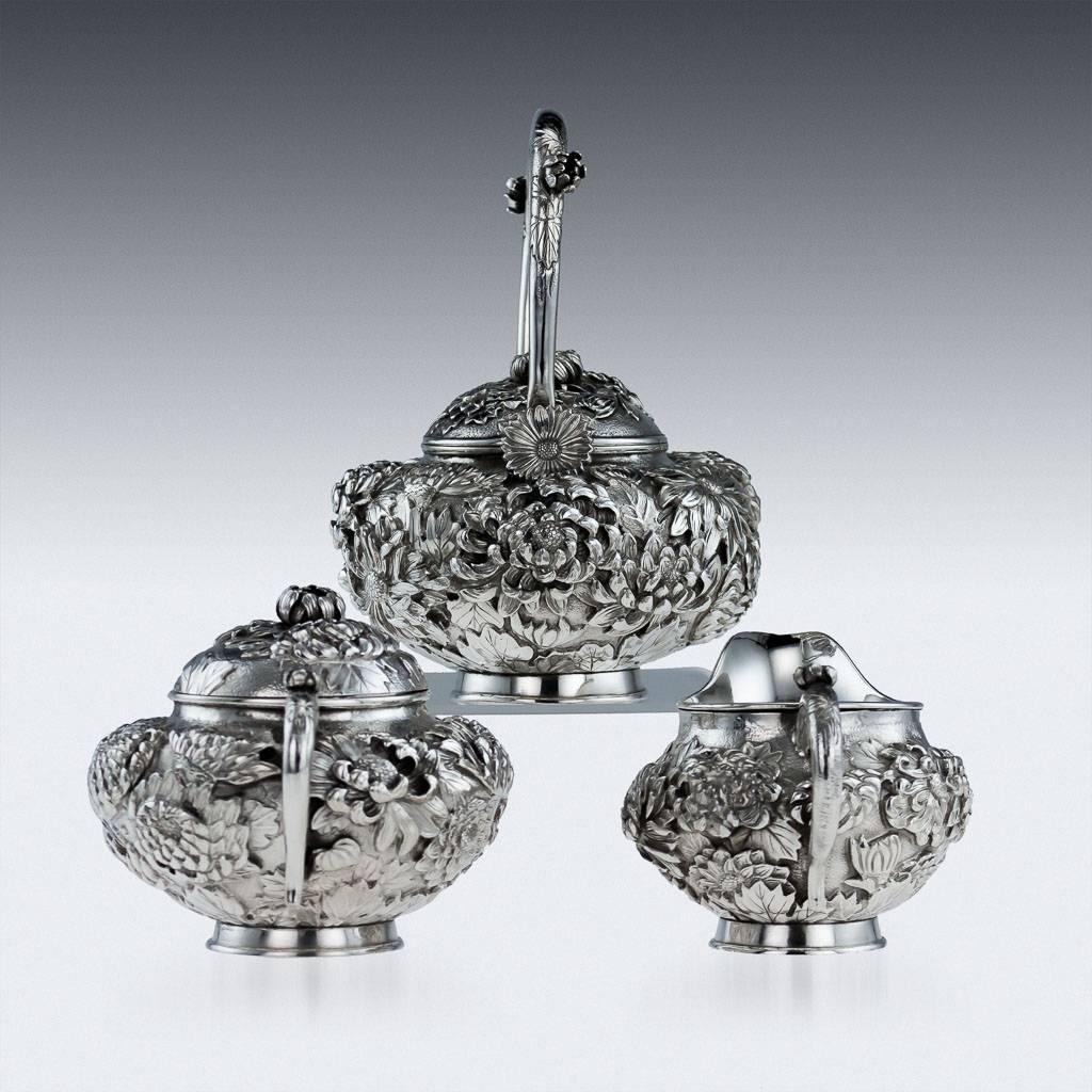 Antique 19th century Japanese Meiji period solid silver three piece tea set, double-skinned, the sides chased in relief with chrysanthemums all on matted ground, teapot and sugar bowl lids applied with realistically modeled floral finials and the