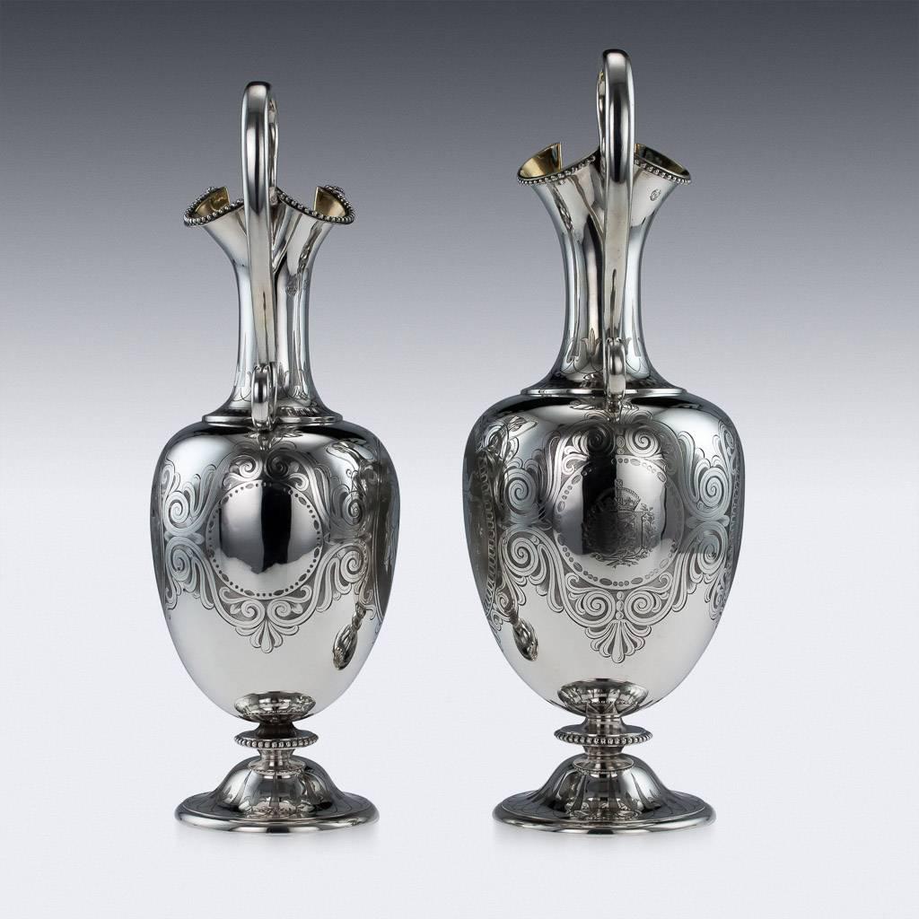 Description

Antique 19th century Victorian solid silver pair of matched wine jugs, of baluster form, scroll handle, bright-cut engraved with scrolling foliage surrounding figural medallions, beaded boarders along the spout, standing on circular