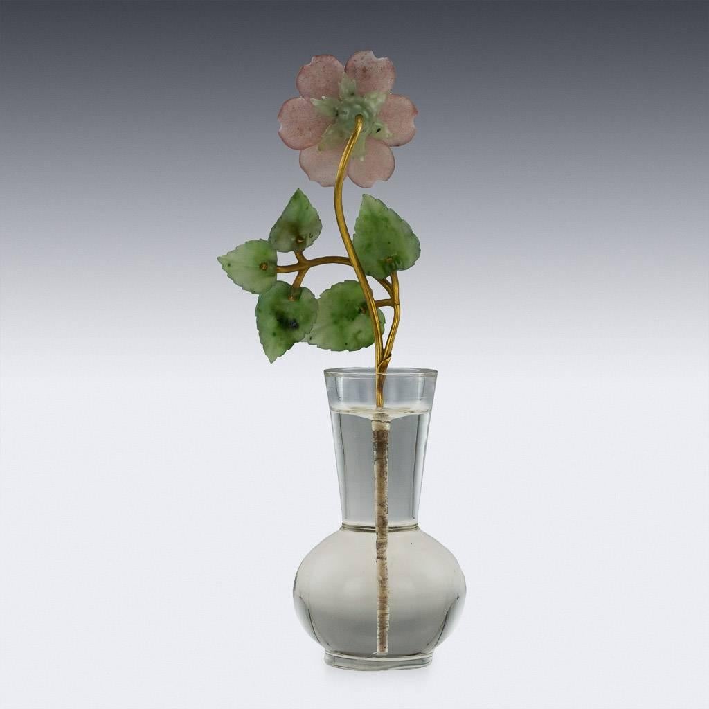 A Faberge style hard-stone carved study of a flower, the petals intricately carved from rose quarts, the leaves from nephrite, the textured branches made of solid 14-carat gold and the center of the flower mounted with a clean and bright 0.20 carat