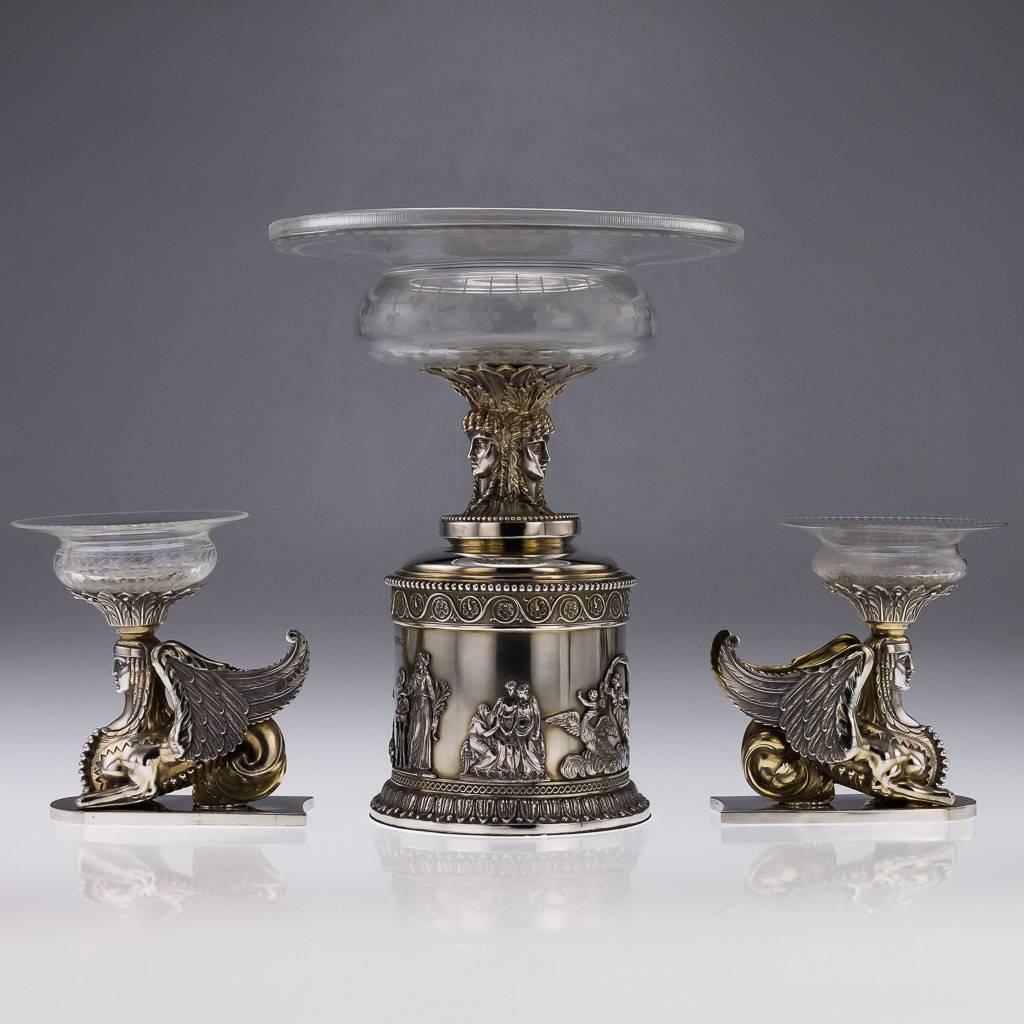 Description

Antique 19th century rare and magnificent Victorian Solid Silver three-piece table garniture, the cylindrical central piece applied with a cast Neoclassical frieze depicting mythological figures, surmounted by a triple-headed Greek