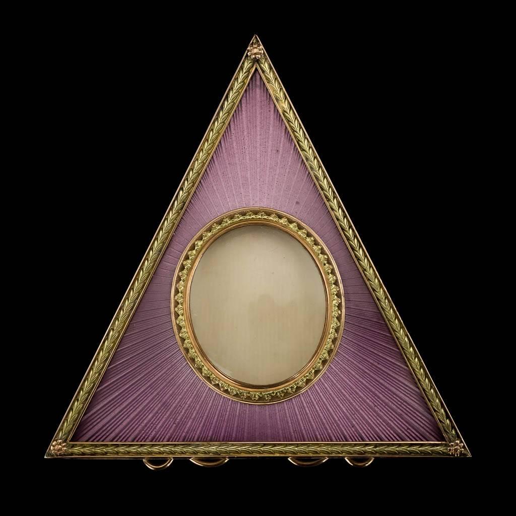 20th century Faberge style two-color gold-mounted and guilloche enamel photograph frame, Triangular shape, enameled in translucent purple over a sunburst guilloché ground, centring a gold circular aperture, all within a laurel leaf boarders, resting