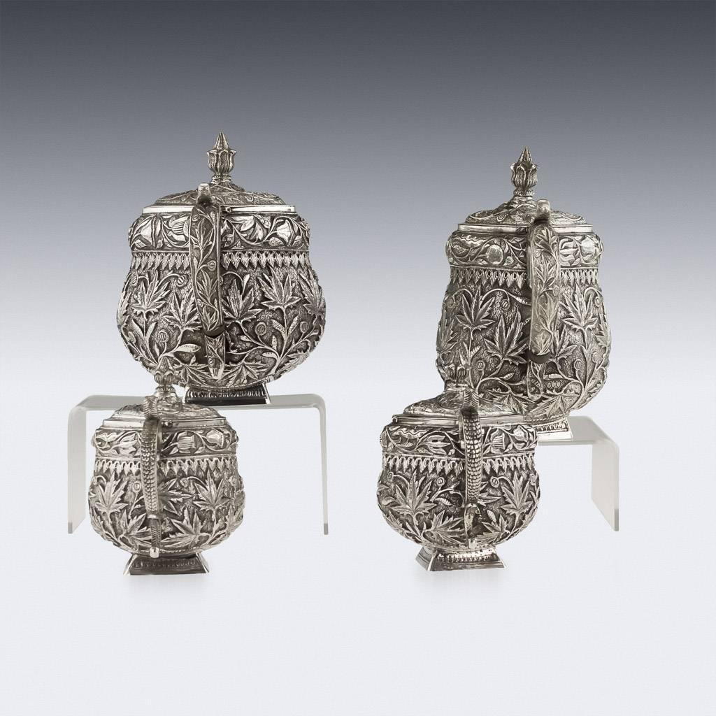 Antique 19th century Indian solid silver four-piece tea and coffee set, profusely and beautifully decorated with the typically Kashmiri stylized foliage known as chinar leaves and meandering vine, each piece standing on a square foot. The set is