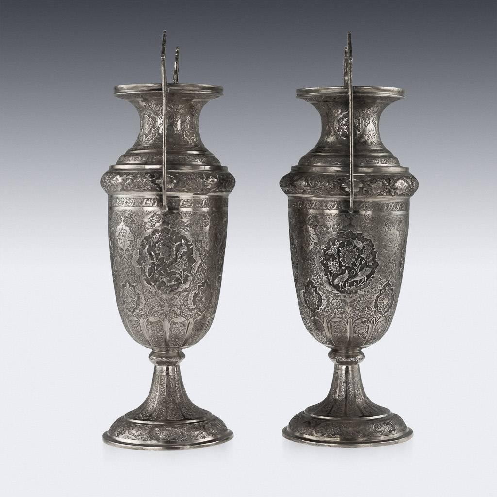Antique 20th century Persian pair of solid silver vases, impressively large and magnificent, each body of urn shape, profusely repoussed' decorated with different scenes and floral motifs on a finely tooled background. Not Hallmarked, but tested