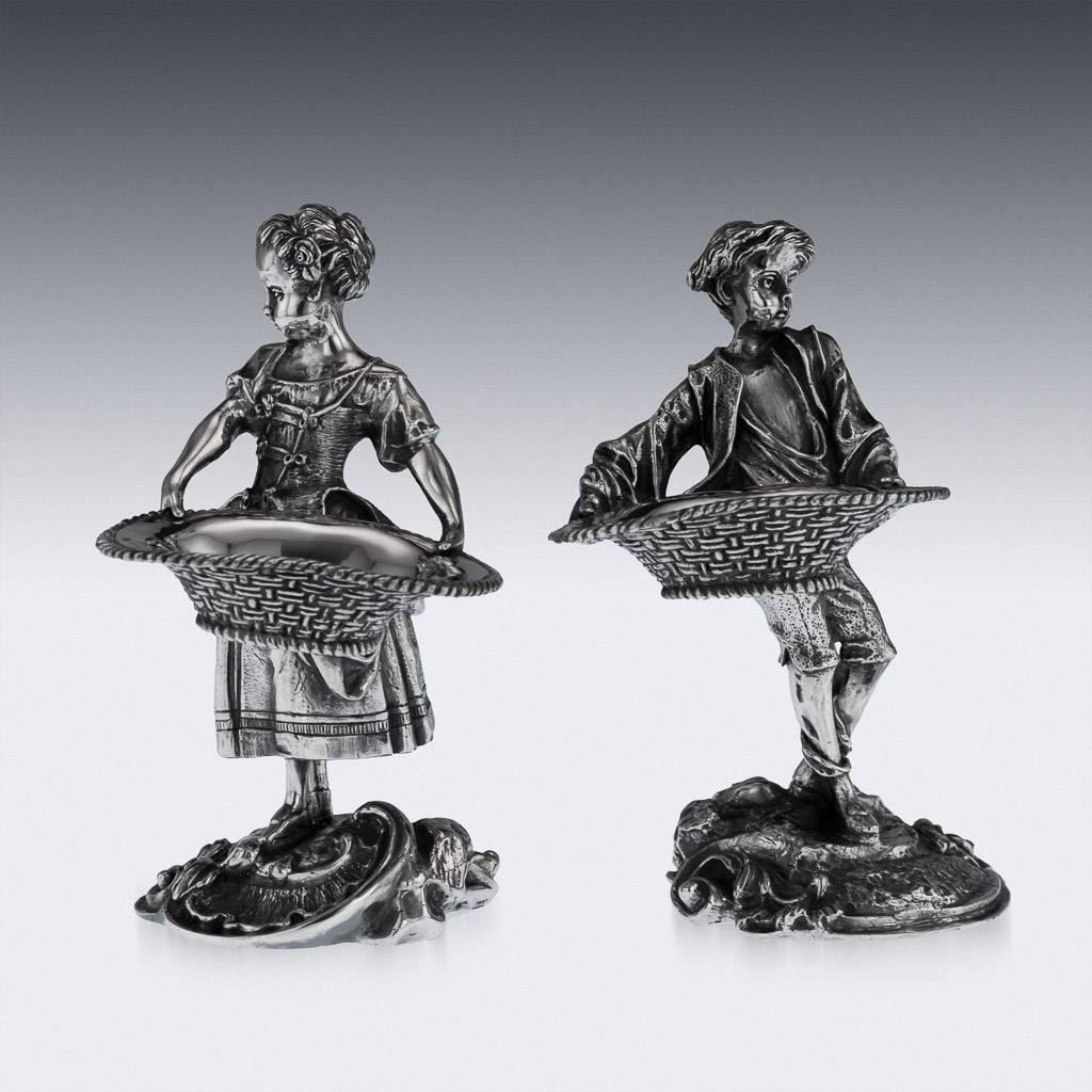 Antique 19th century Scottish rare pair of novelty cast solid silver table salt-cellars, formed as a female and male gardeners dressed in 18th century costume, standing on an elaborate Rococo designed base and both holding a woven basket. Both