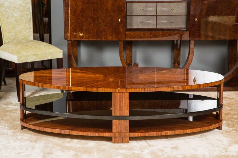 Oval Art Deco style coffee table made by German fine furniture maker Cygal Art Deco. The top is made of intricately laid Laurel veneer, starburst design meeting in diamond center, off set by a center shelf in black high gloss, this design repeats at
