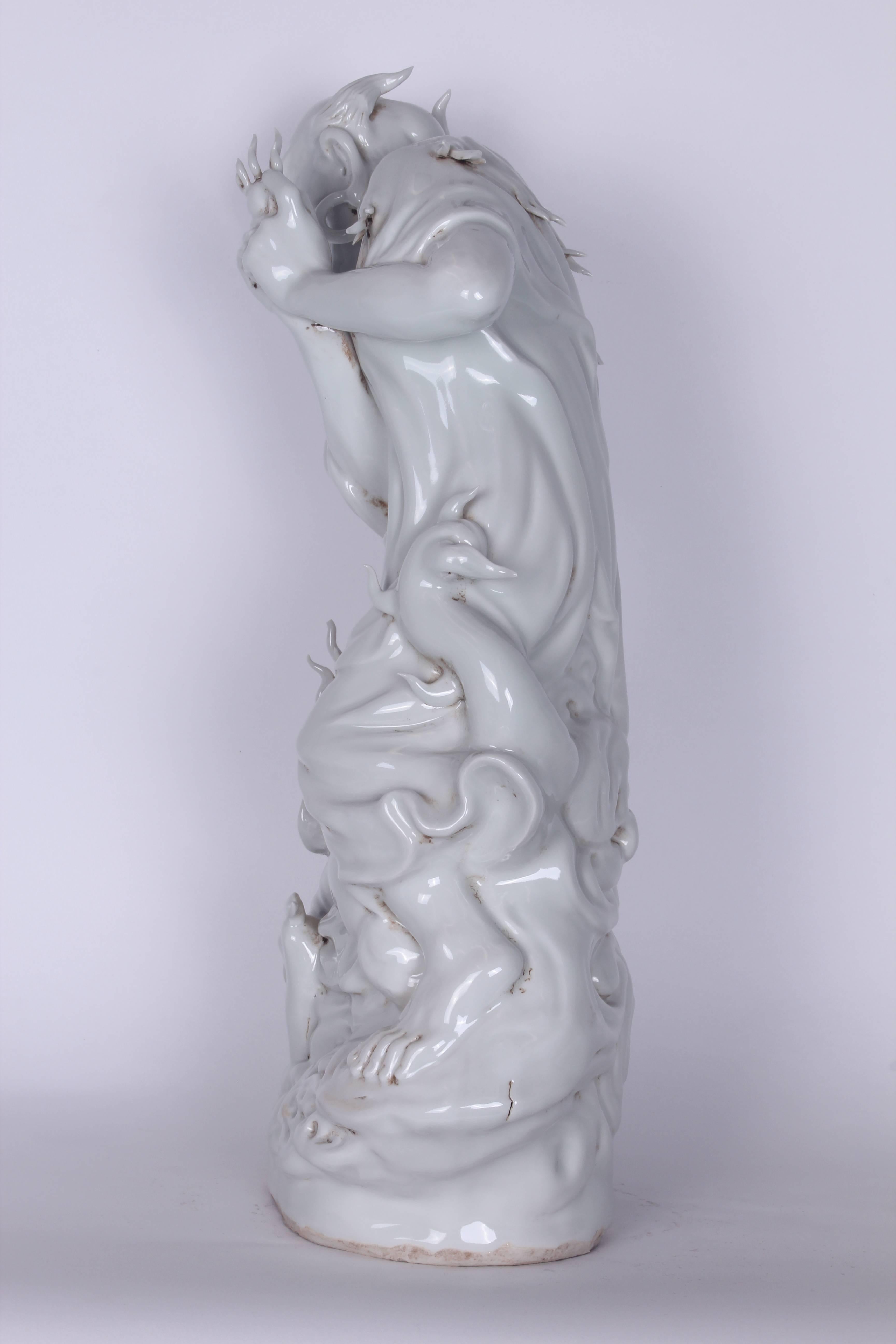 Vintage Blanc de Chine Chinese Diety porcelain holding flame standing over dragon.