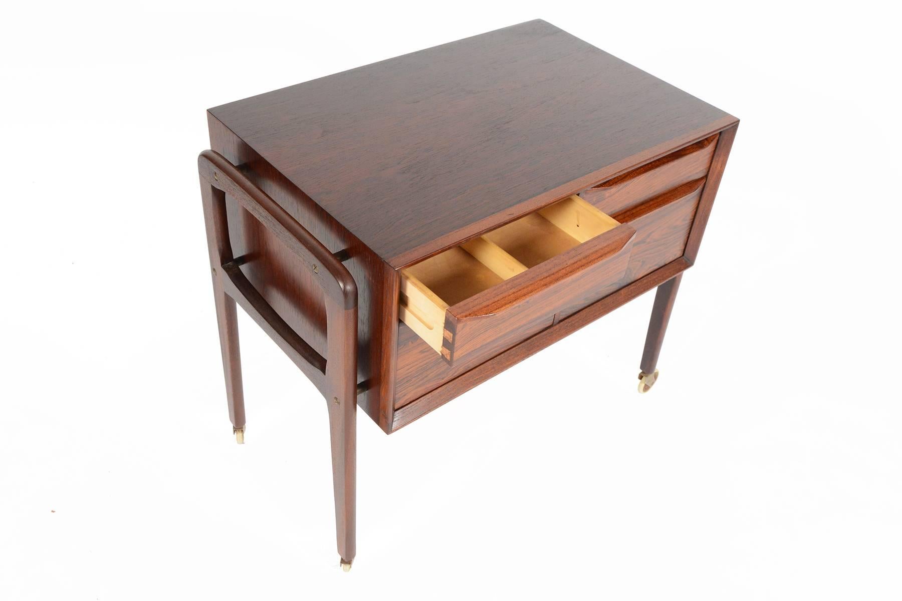 This Danish modern midcentury four drawer sewing cart in rosewood will be a wonderful addition to any modern home. This cart can be used for its original intention as a sewing cart or can easily transform into a striking bar cart. This well built
